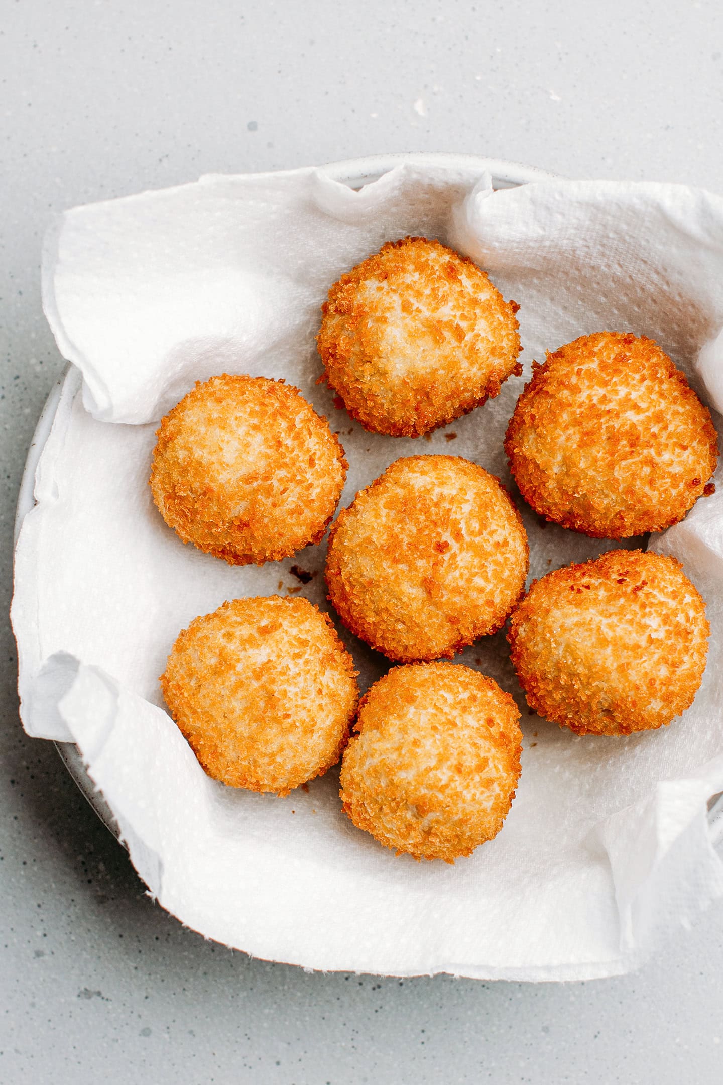 Fried cheese balls on a plate lined with kitchen paper towels.