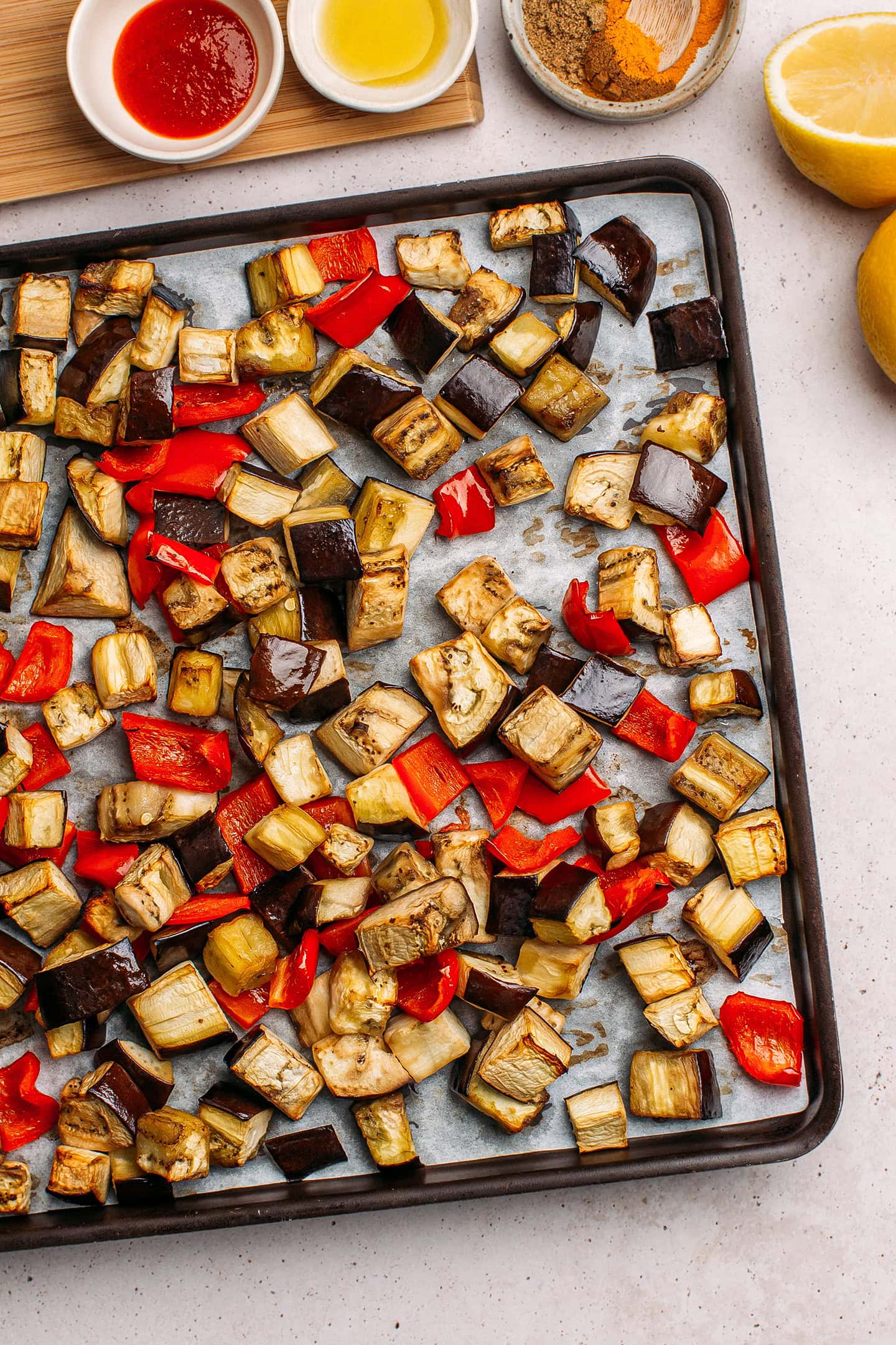 Roasted eggplant and red bell pepper on a baking sheet.