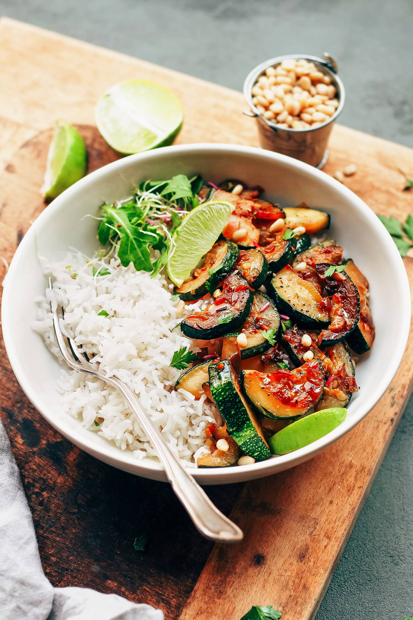 Bowl containing caramelized zucchini slices, white rice, and salad.