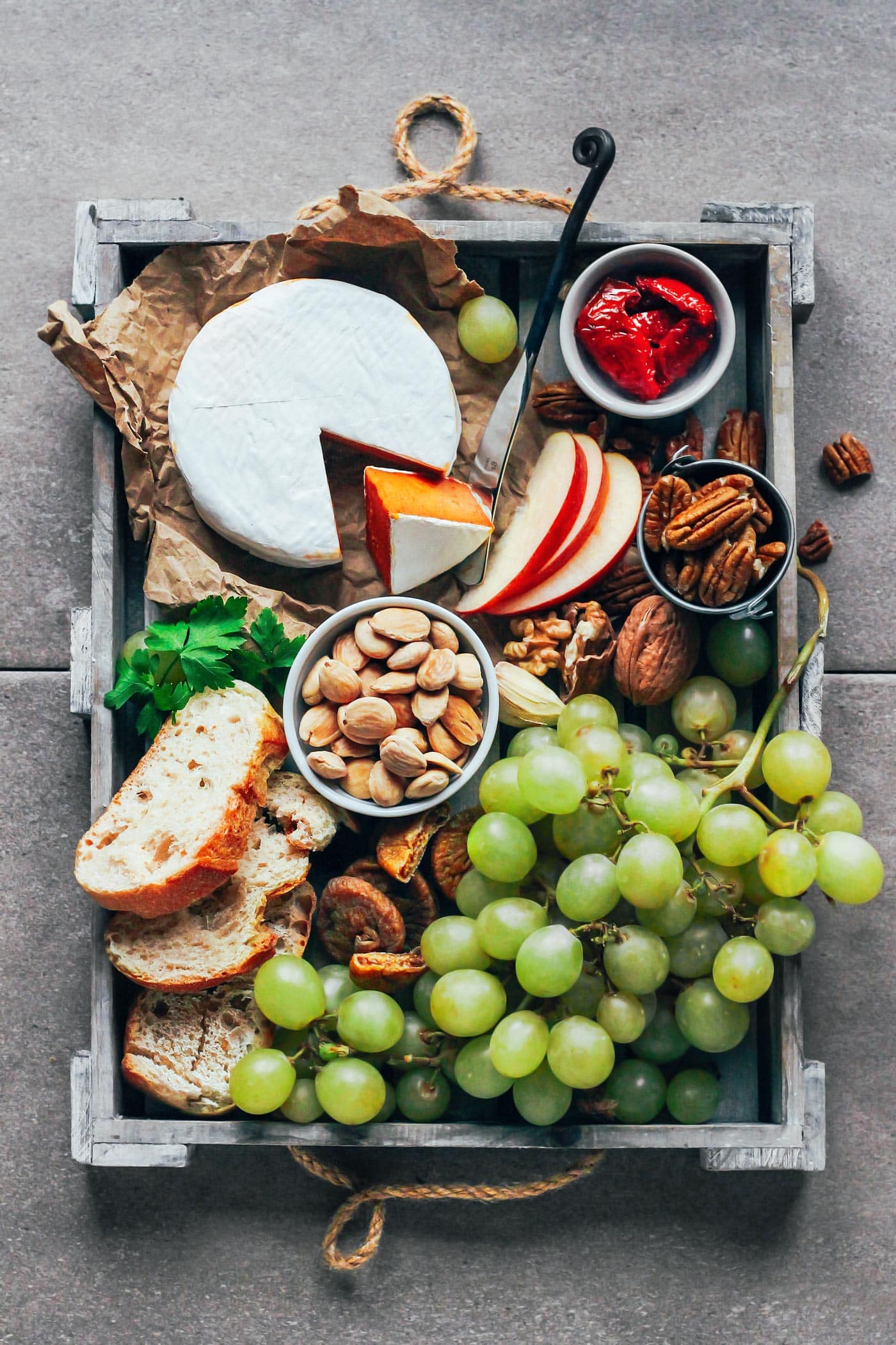 Cheese platter with grapes, bread, almonds, fruits, and vegan camembert.