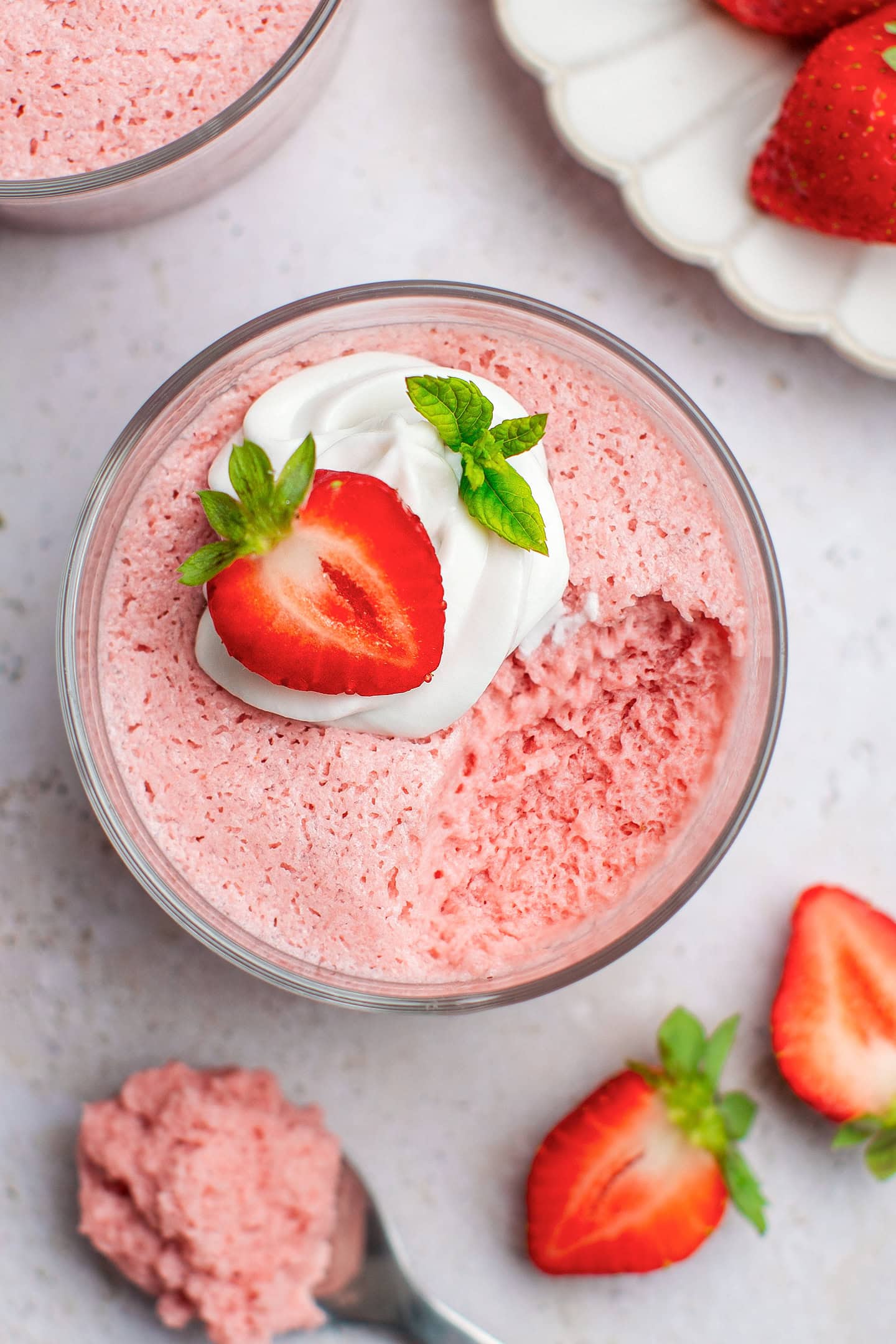 Vegan strawberry mousse topped with coconut cream and a strawberry.