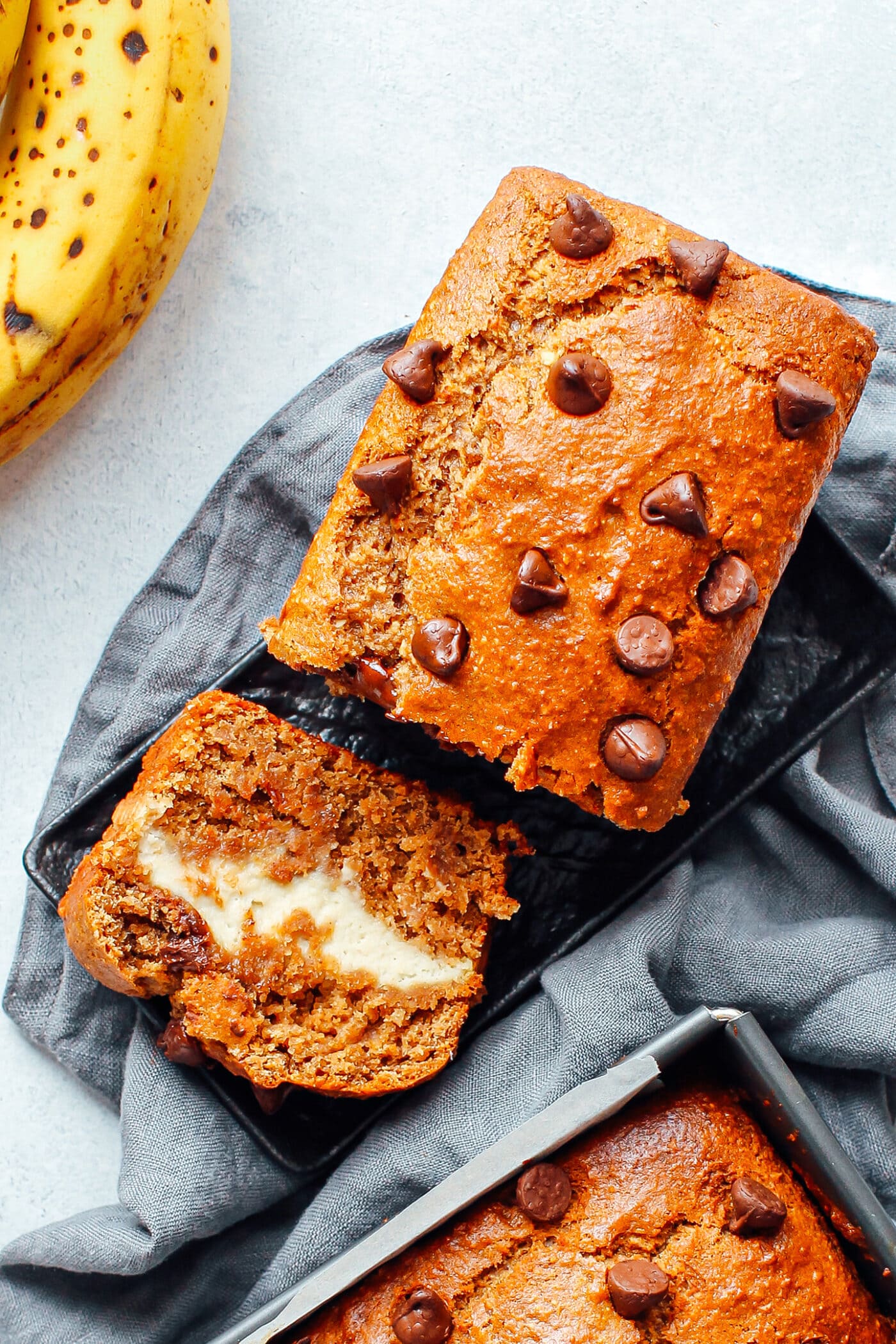 Vegan banana bread with a layer of cream cheese on a plate.