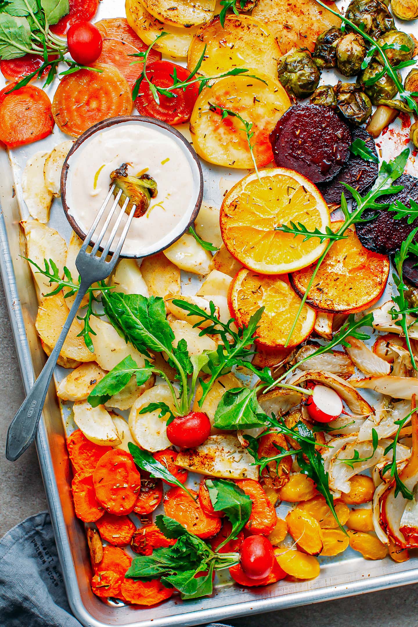 Roasted vegetables like beets, fennel, parsnips, and carrots, on a baking sheet.