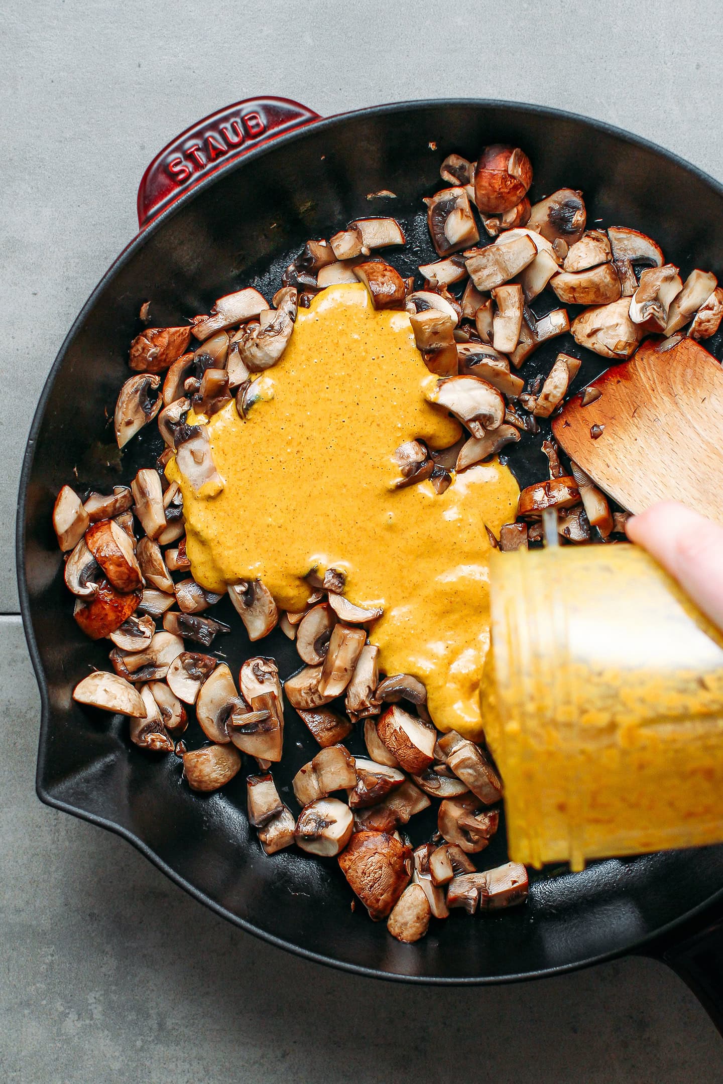 Pouring satay sauce over sautéed mushrooms.