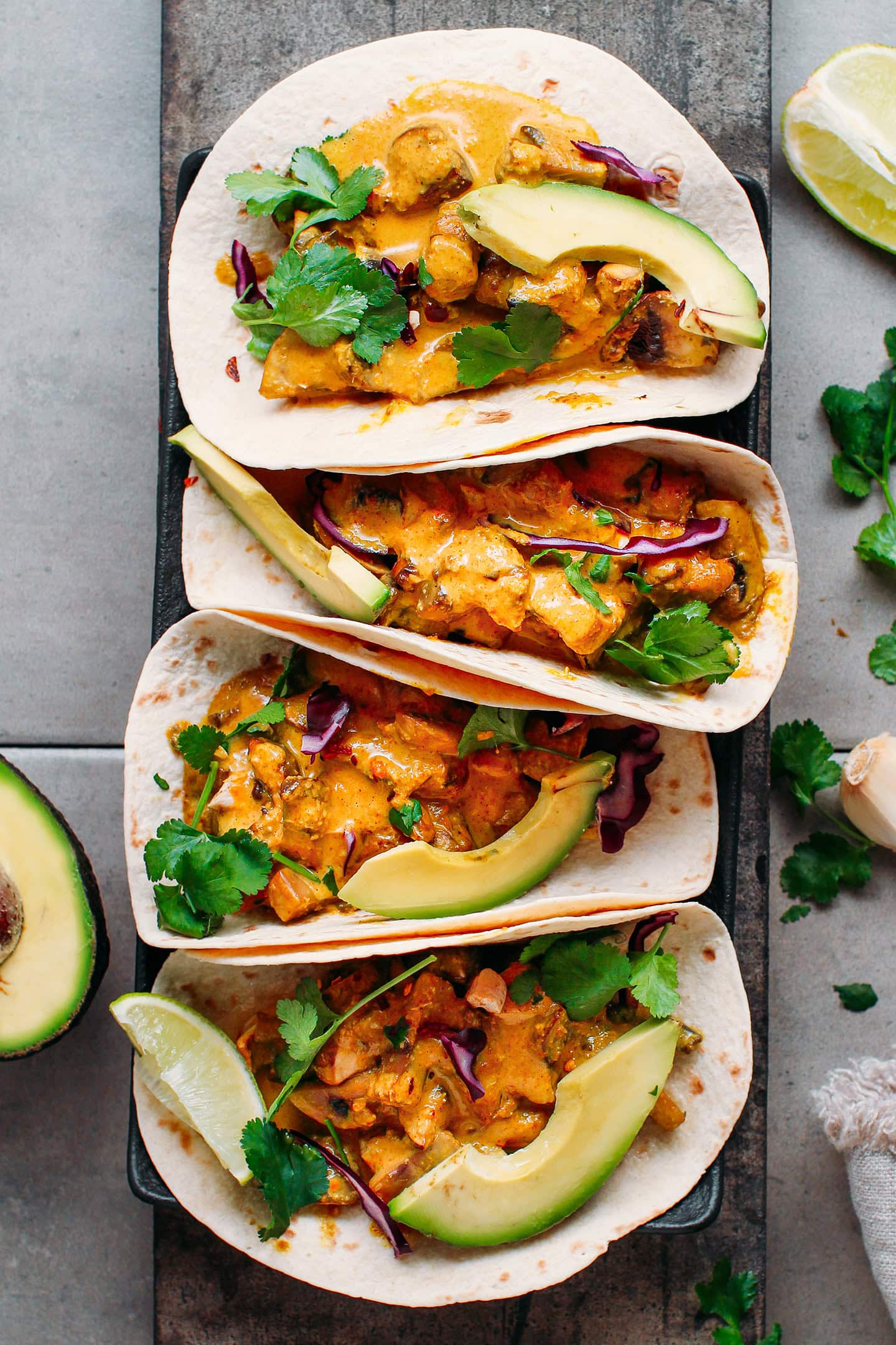 Saucy satay mushroom tacos topped with cilantro, avocado, and red cabbage.