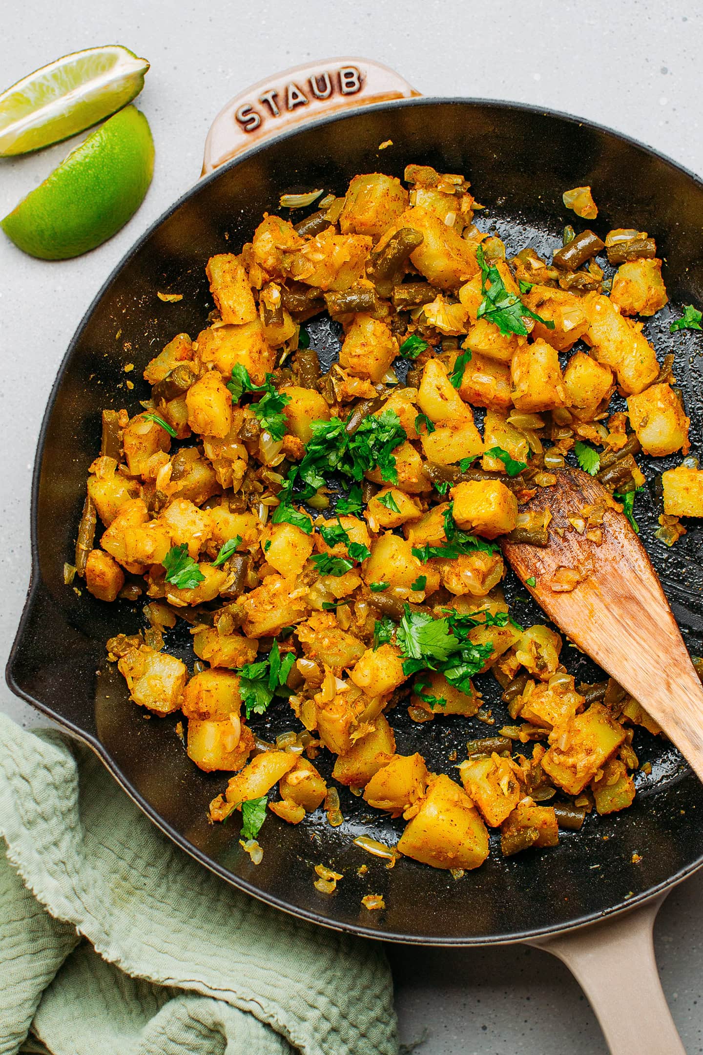 Cooked potatoes, green beans, and spices in a skillet.