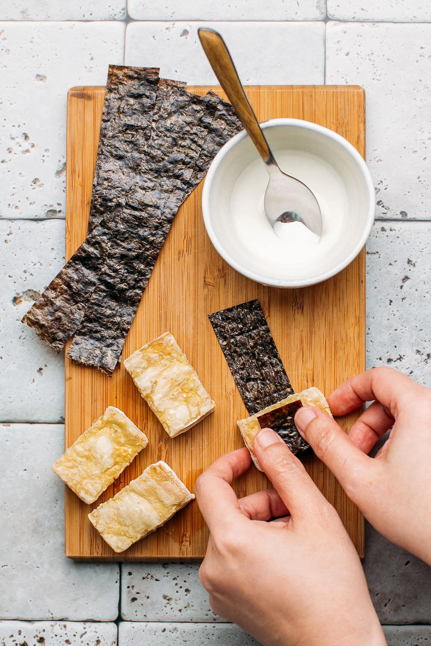 Wrapping tofu with sheets of nori seaweed.