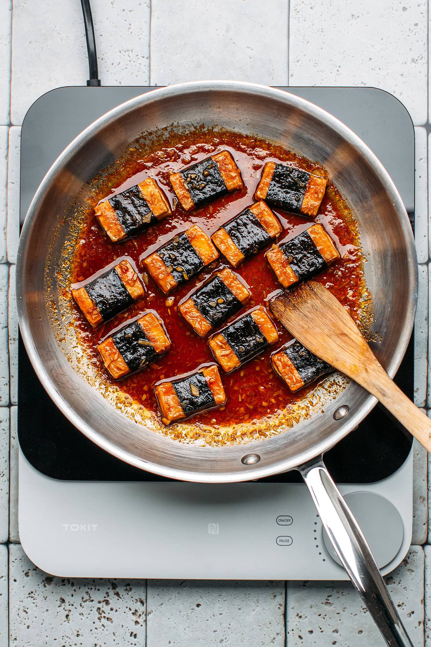 Tofu wrapped in seaweed cooked in a sauce in a pan.