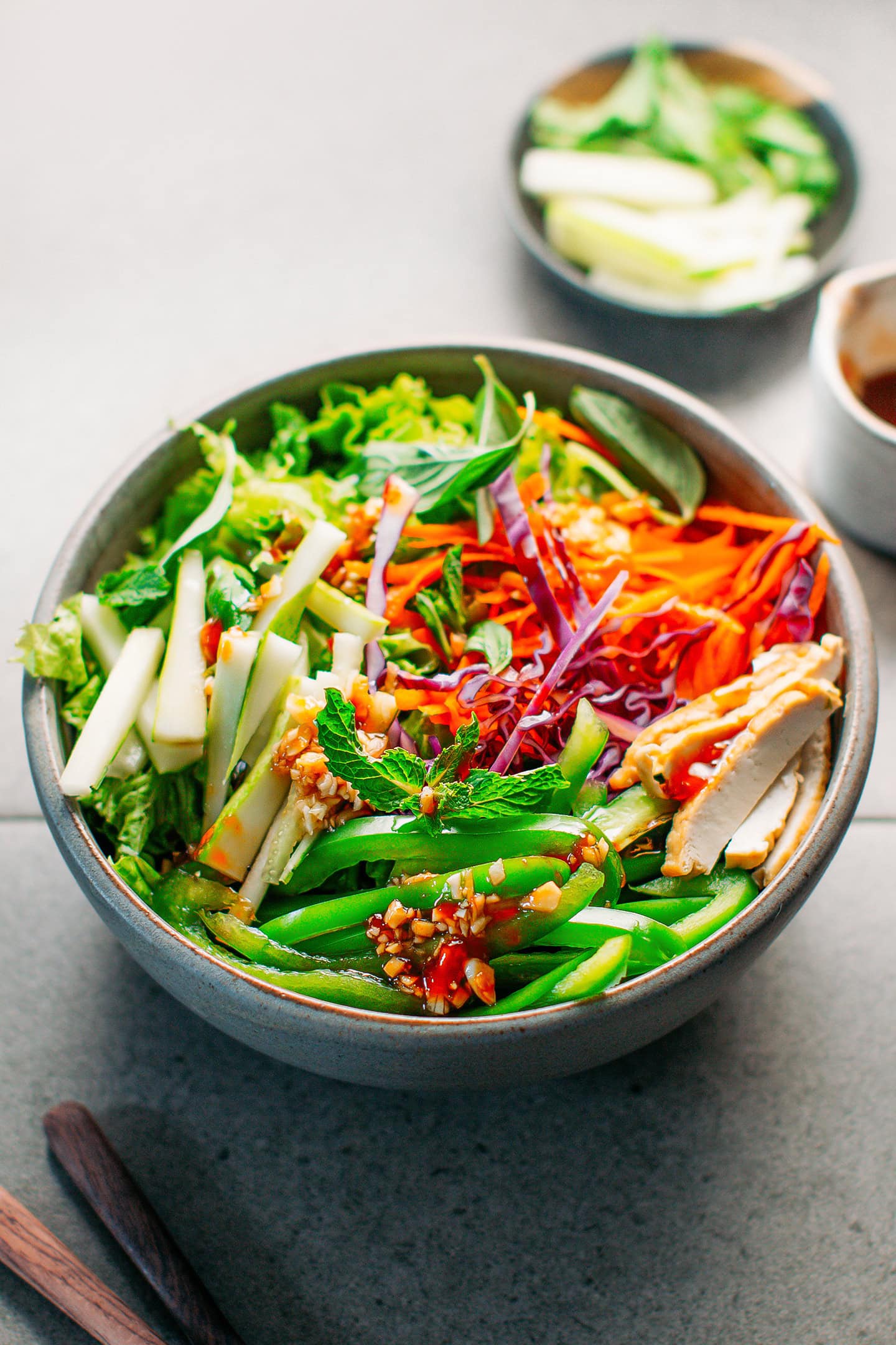 Vegetable salad with cucumber, tofu, bell peppers, mint, and basil, in a bowl.