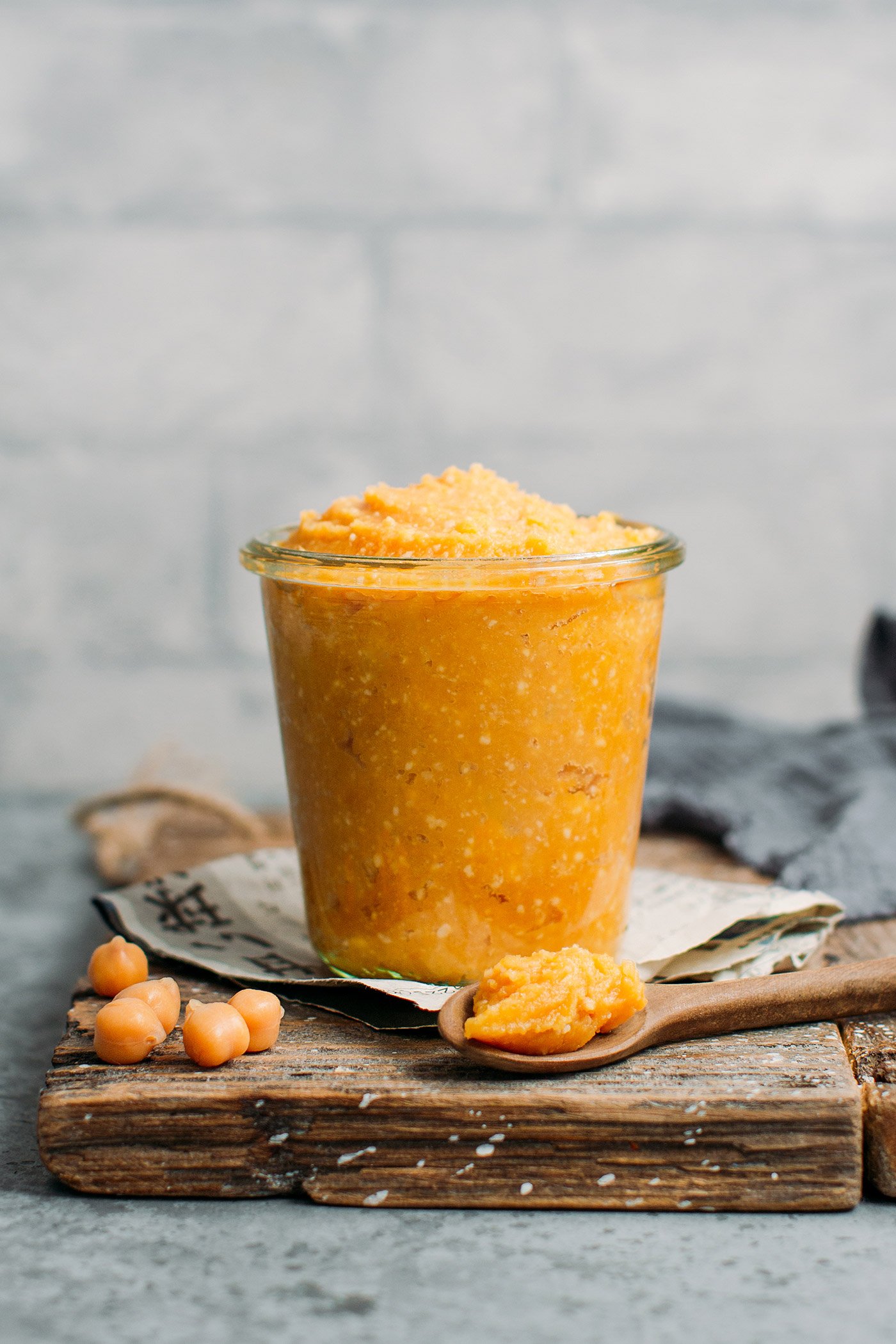 Chickpea miso in a jar on a wooden board.