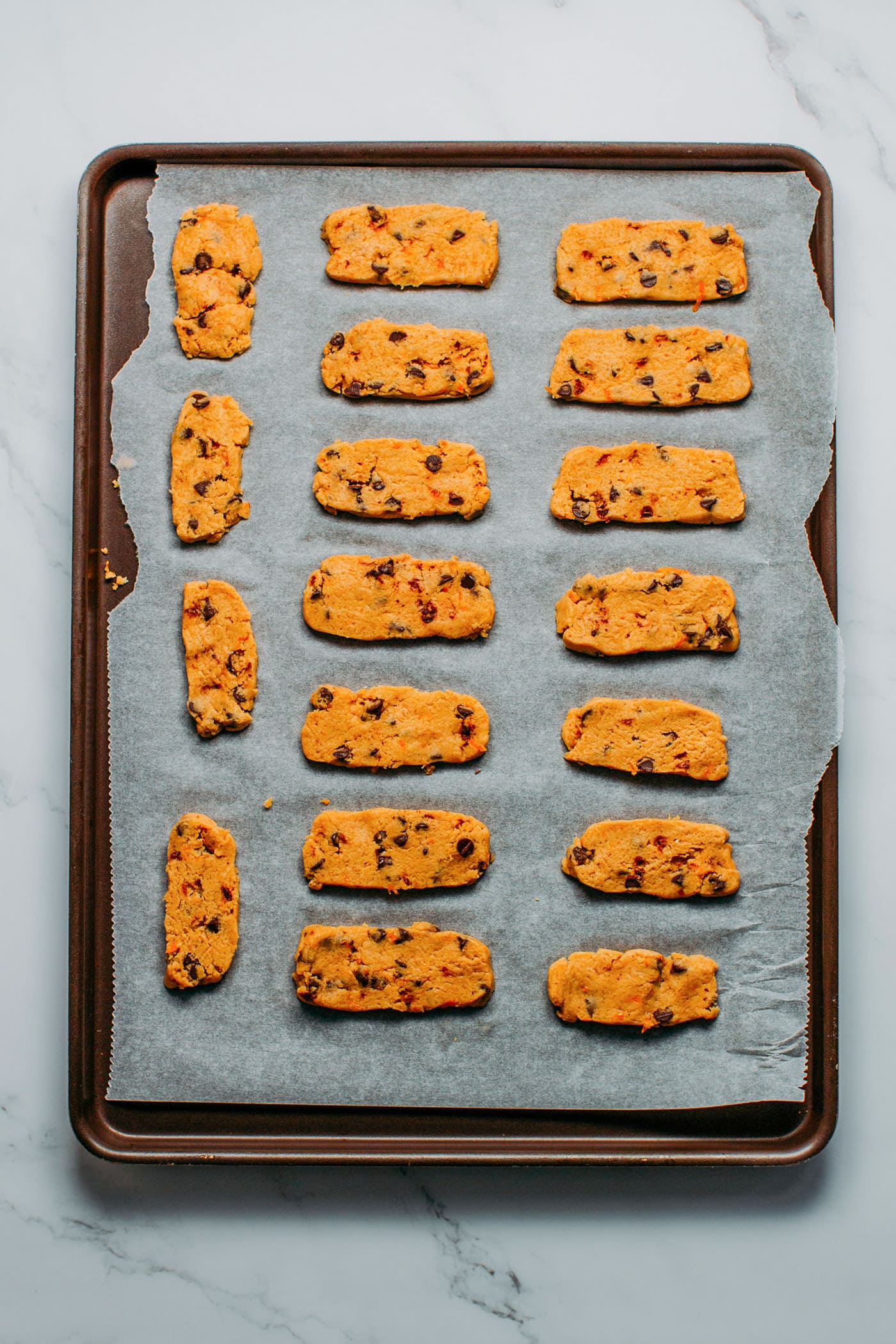 Unbaked long shortbread cookies on a baking sheet.