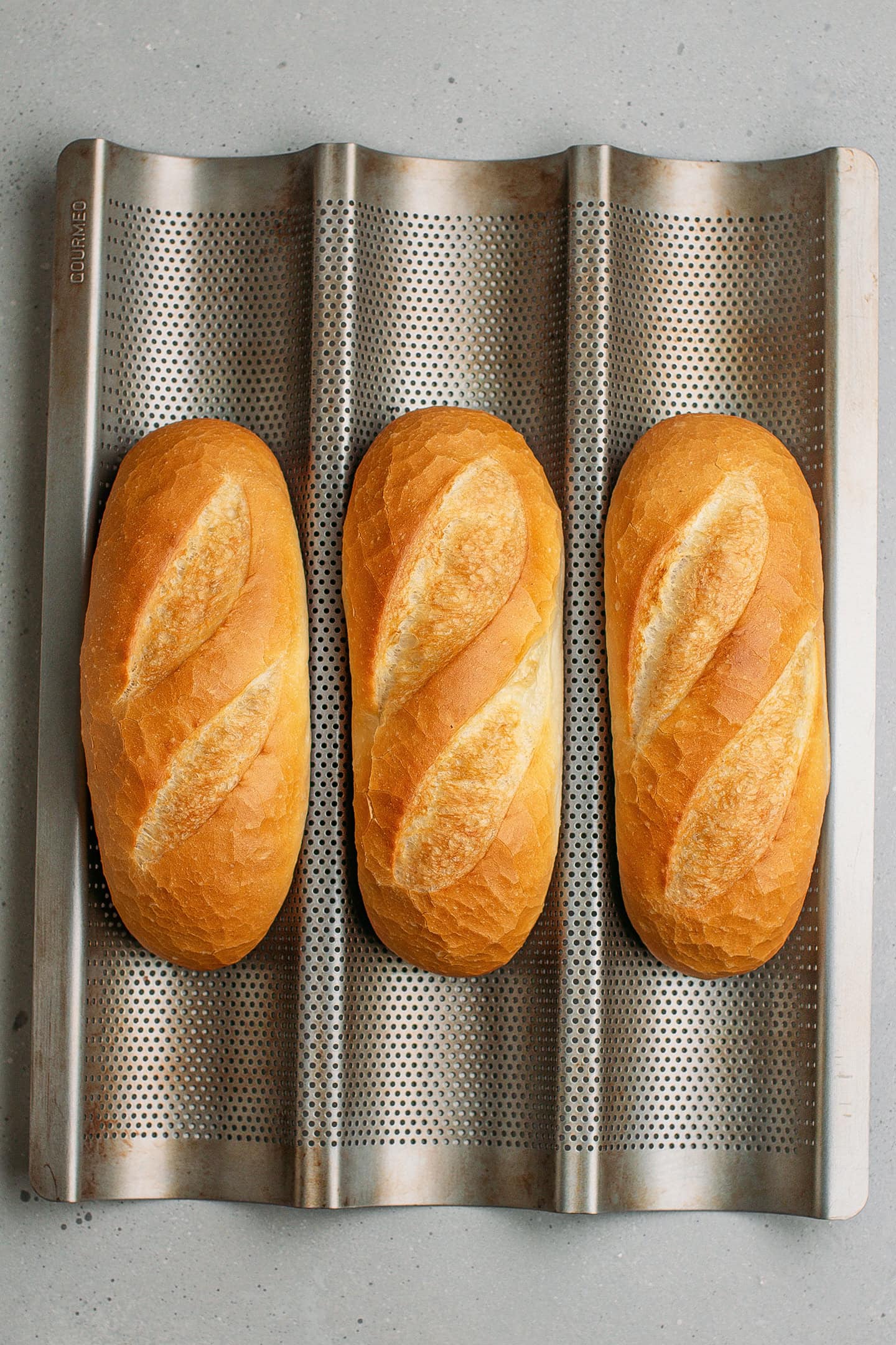 Three banh mi baguettes on a pan.