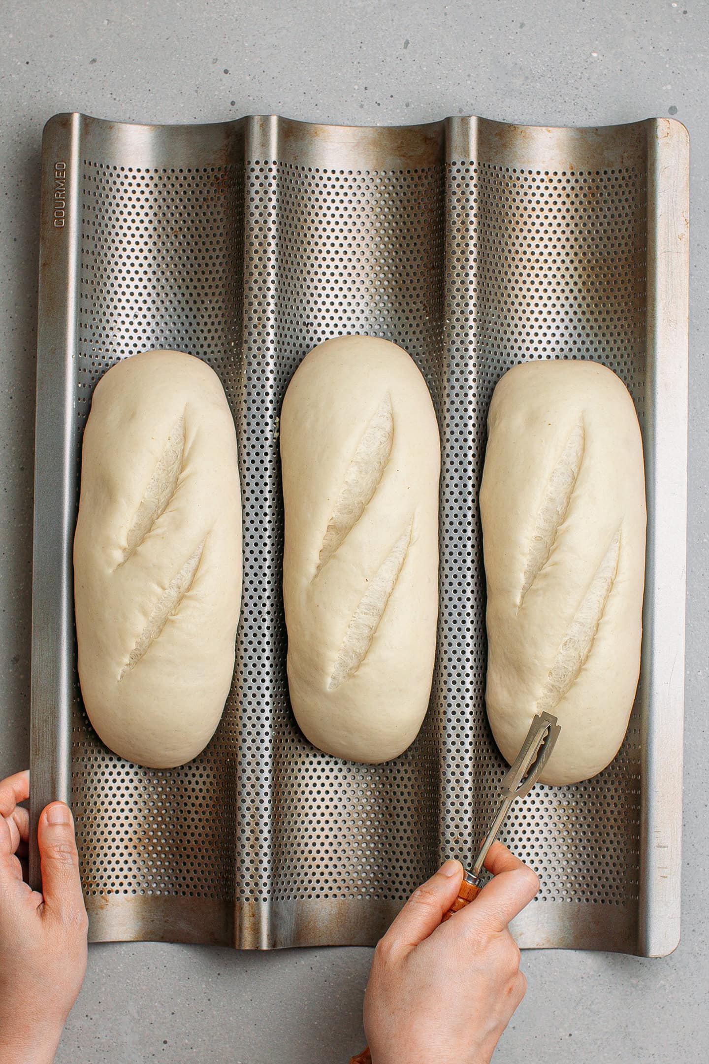 Scoring unbaked baguettes.