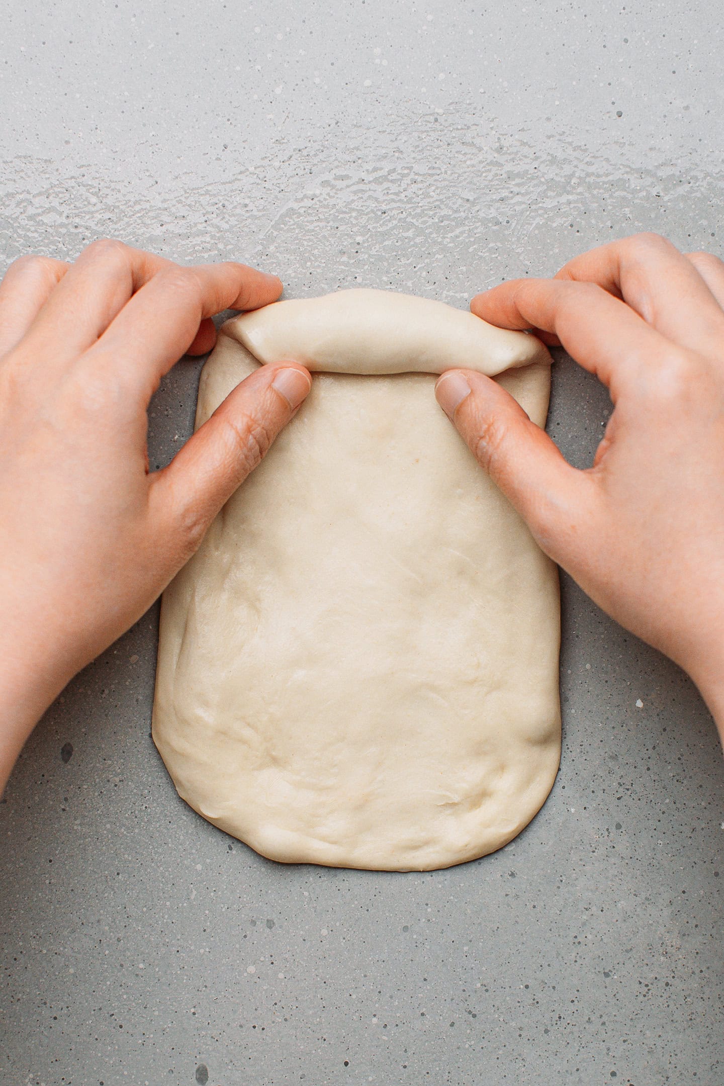 Starting to roll a piece of dough into a log.
