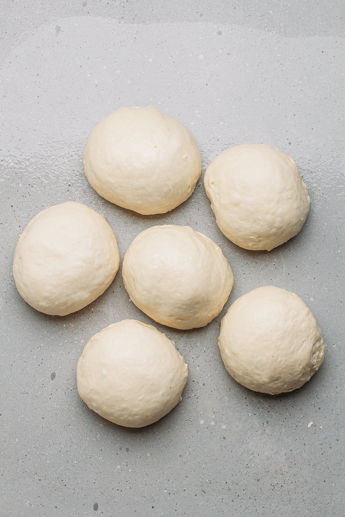 Six balls of dough on a working surface.