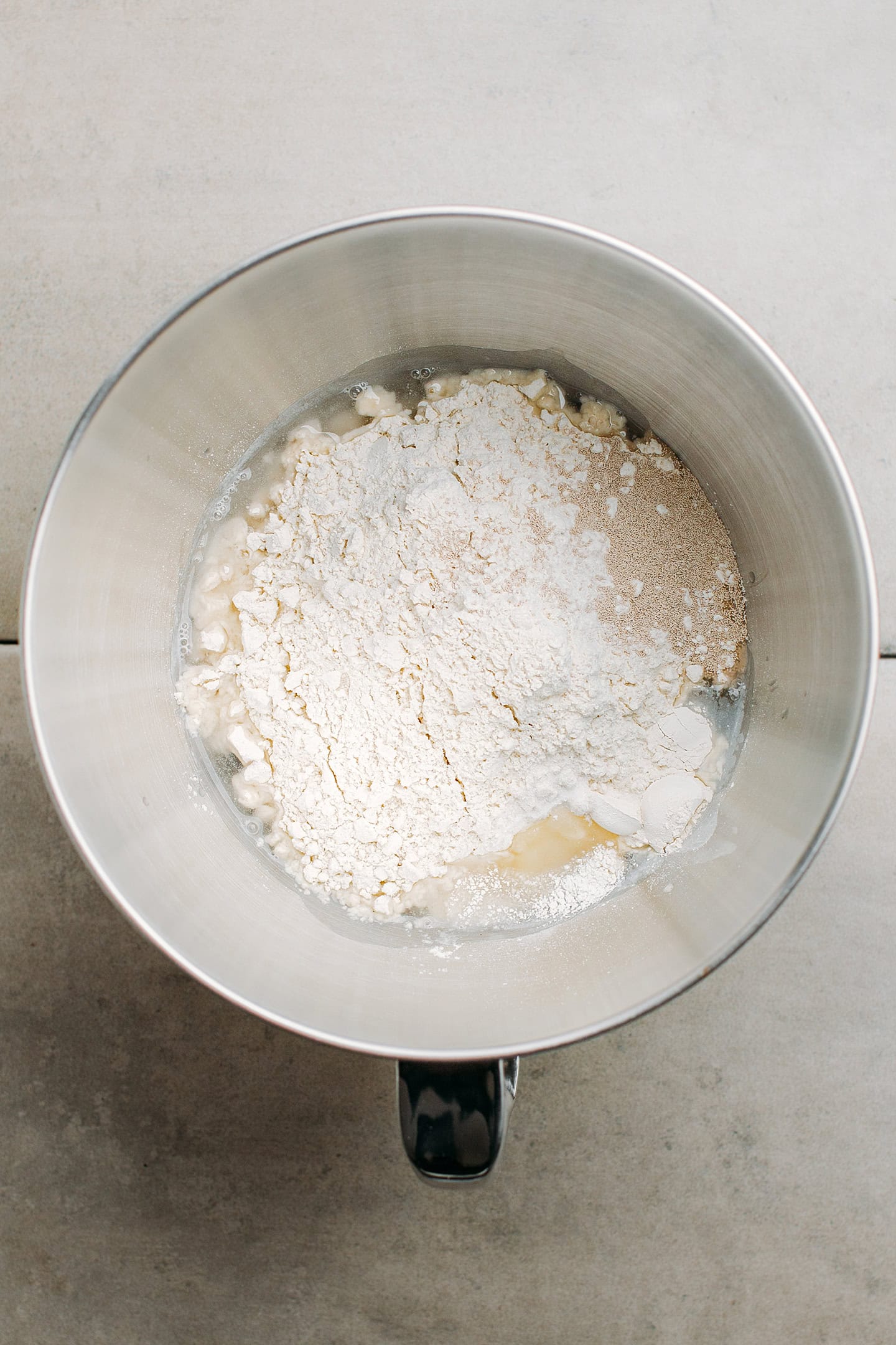 Flour, yeast, sugar, and vitamin c in a stand mixer bowl.