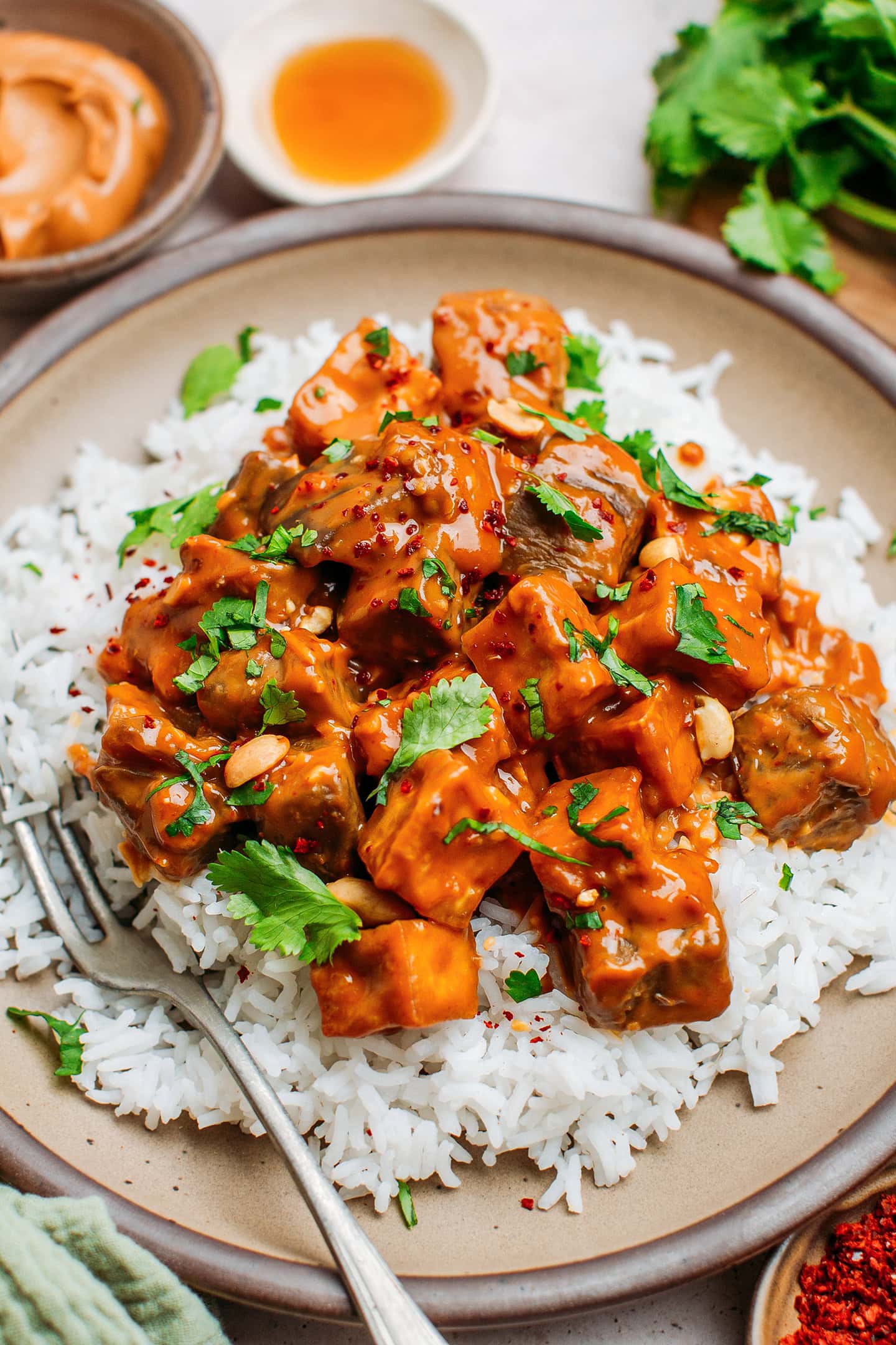 Eggplant and tofu with peanut sauce and rice in a bowl.