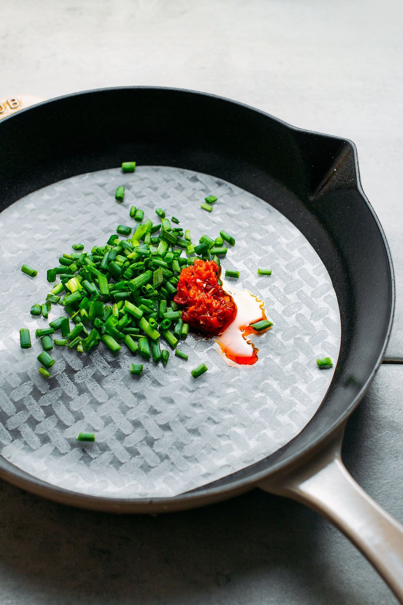 Chopped green onions and saté paste on a rice paper sheet.