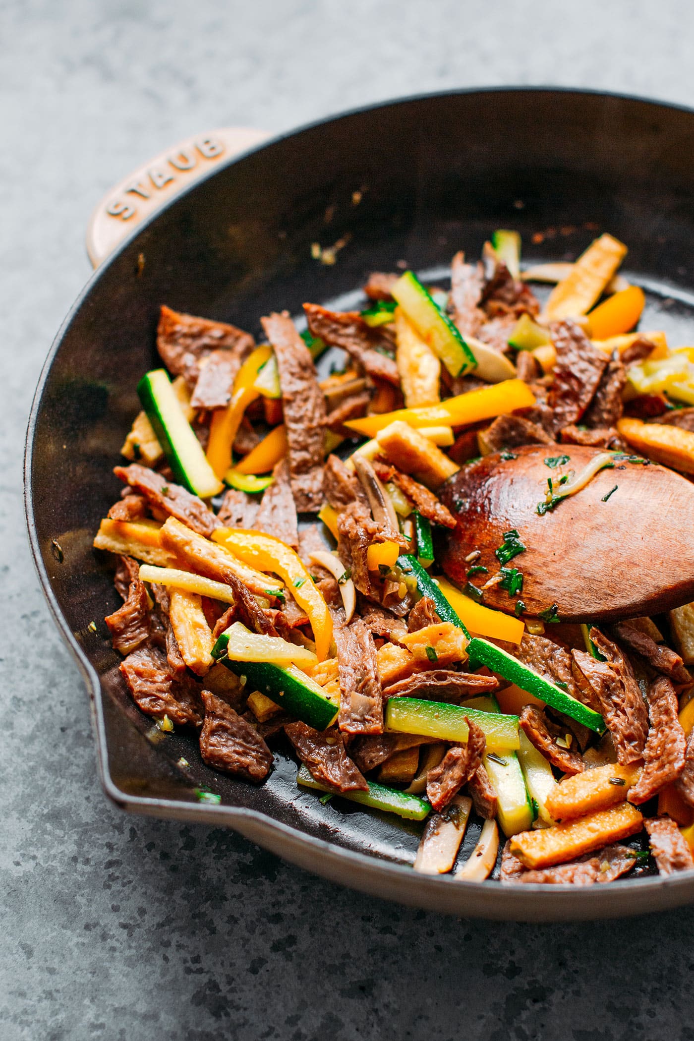 Vegan beef, zucchini, yellow bell pepper, and mushrooms in a skillet.