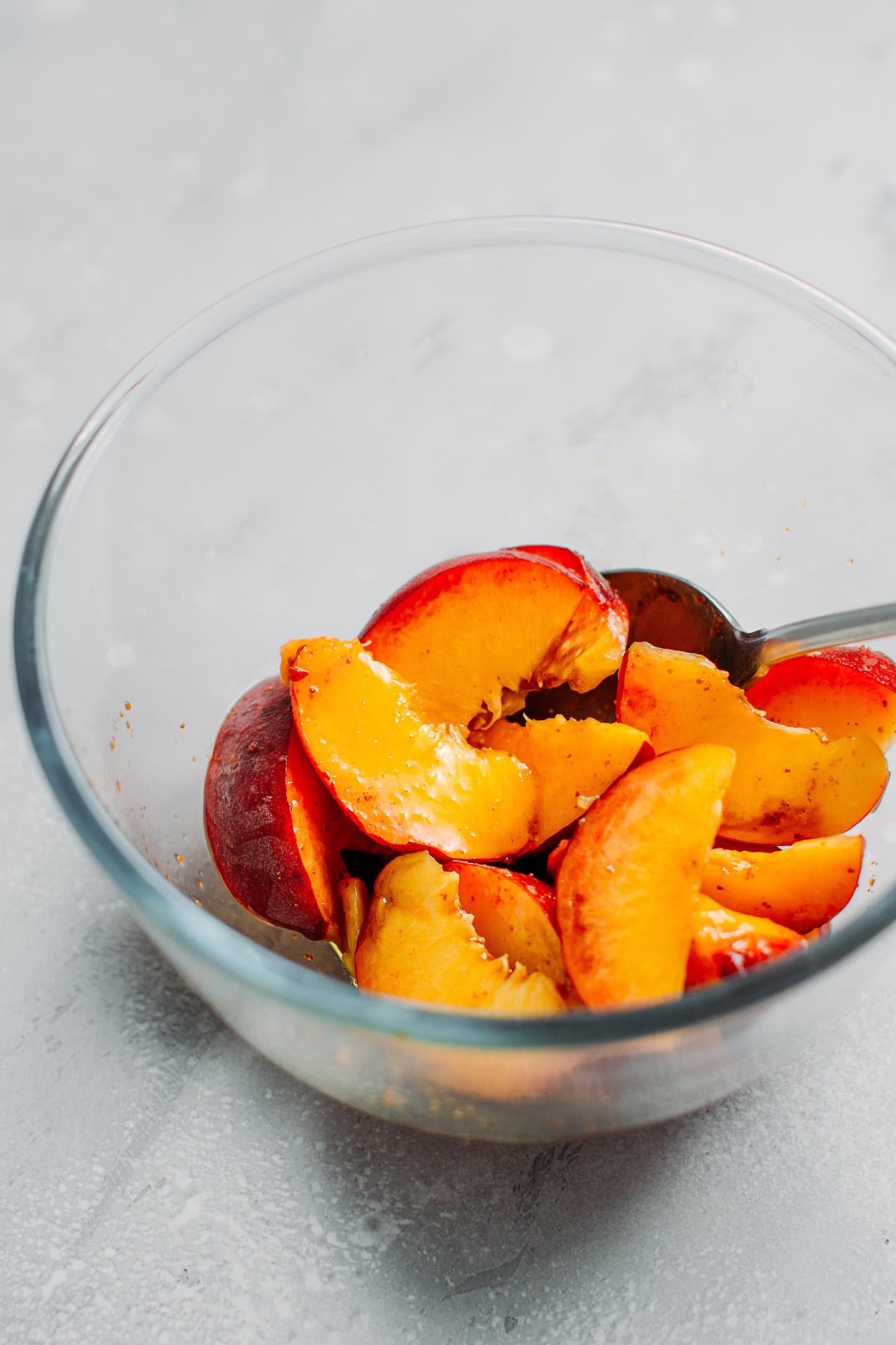 Sliced peaches tossed with sugar in a bowl.