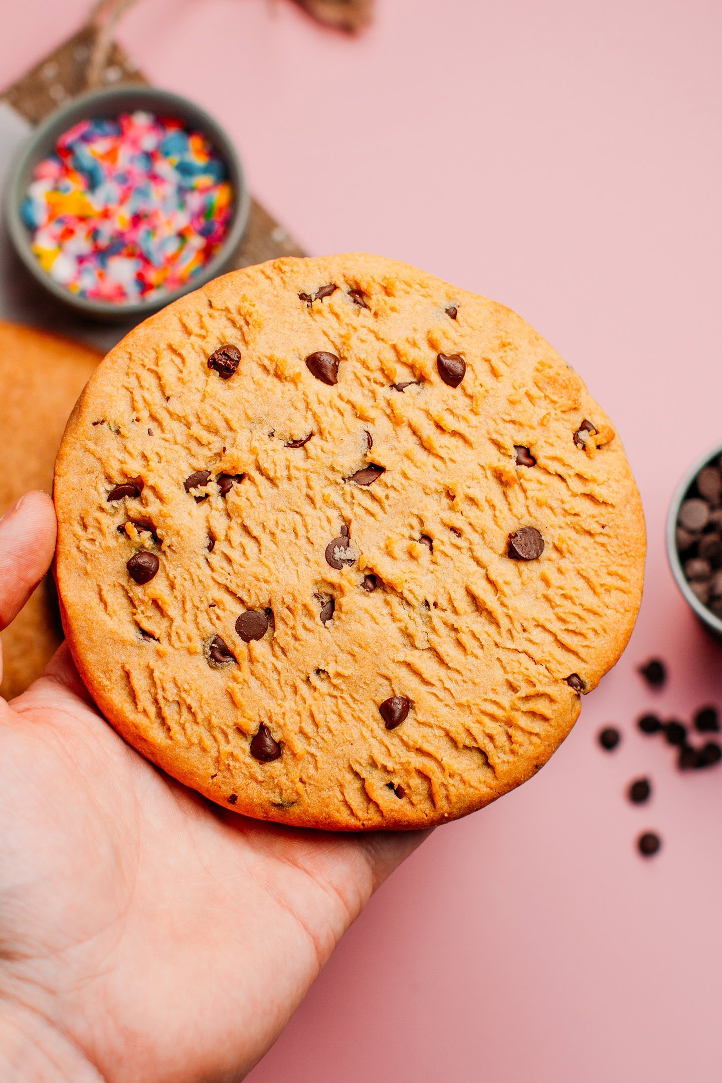 Holding a complete cookie copycat with chocolate chips.