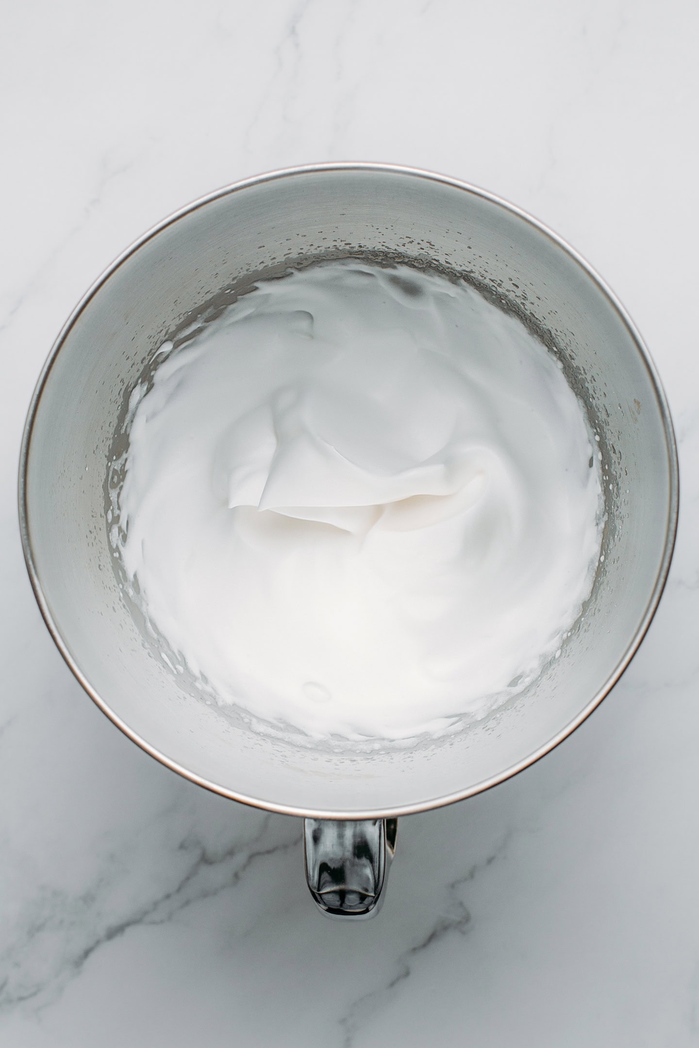 Whipped aquafaba in the bowl of a stand mixer.