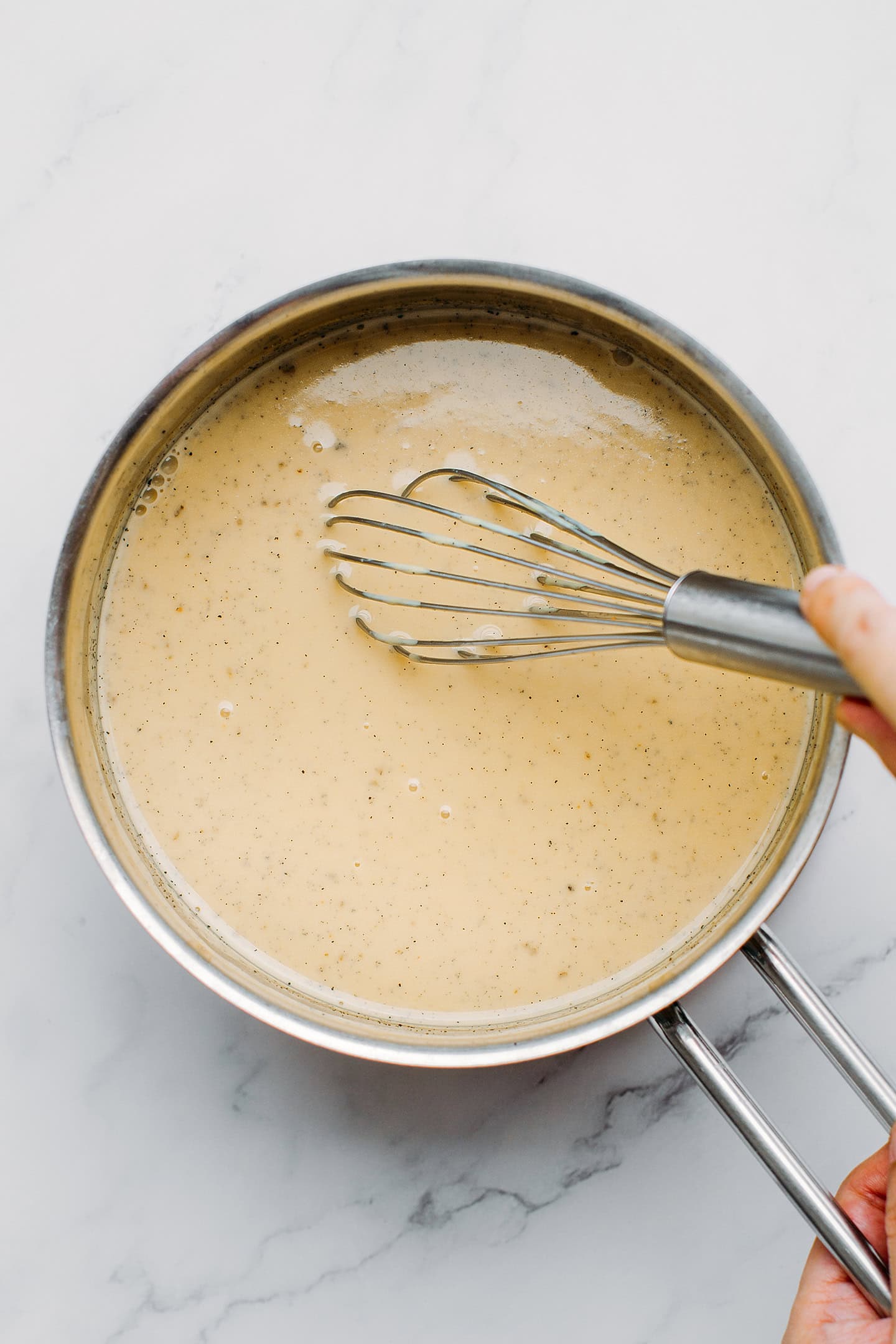 Whisking plant-based milk with vanilla and cornstarch in a saucepan.