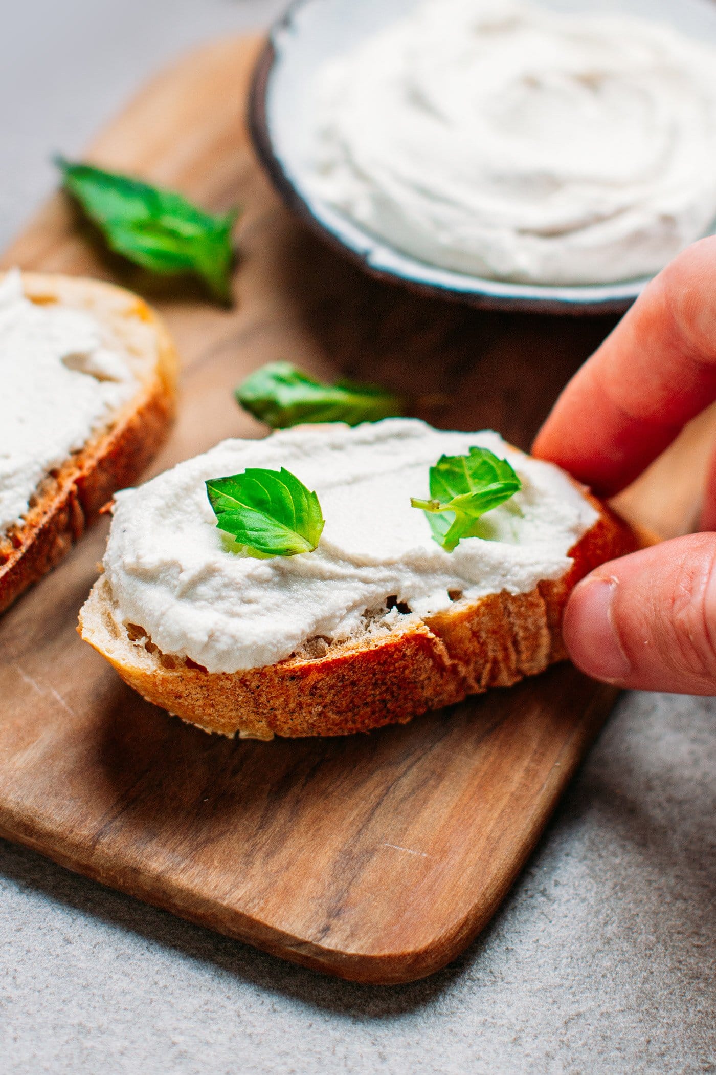 Close-up of vegan cream cheese on a toast with basil leaves.