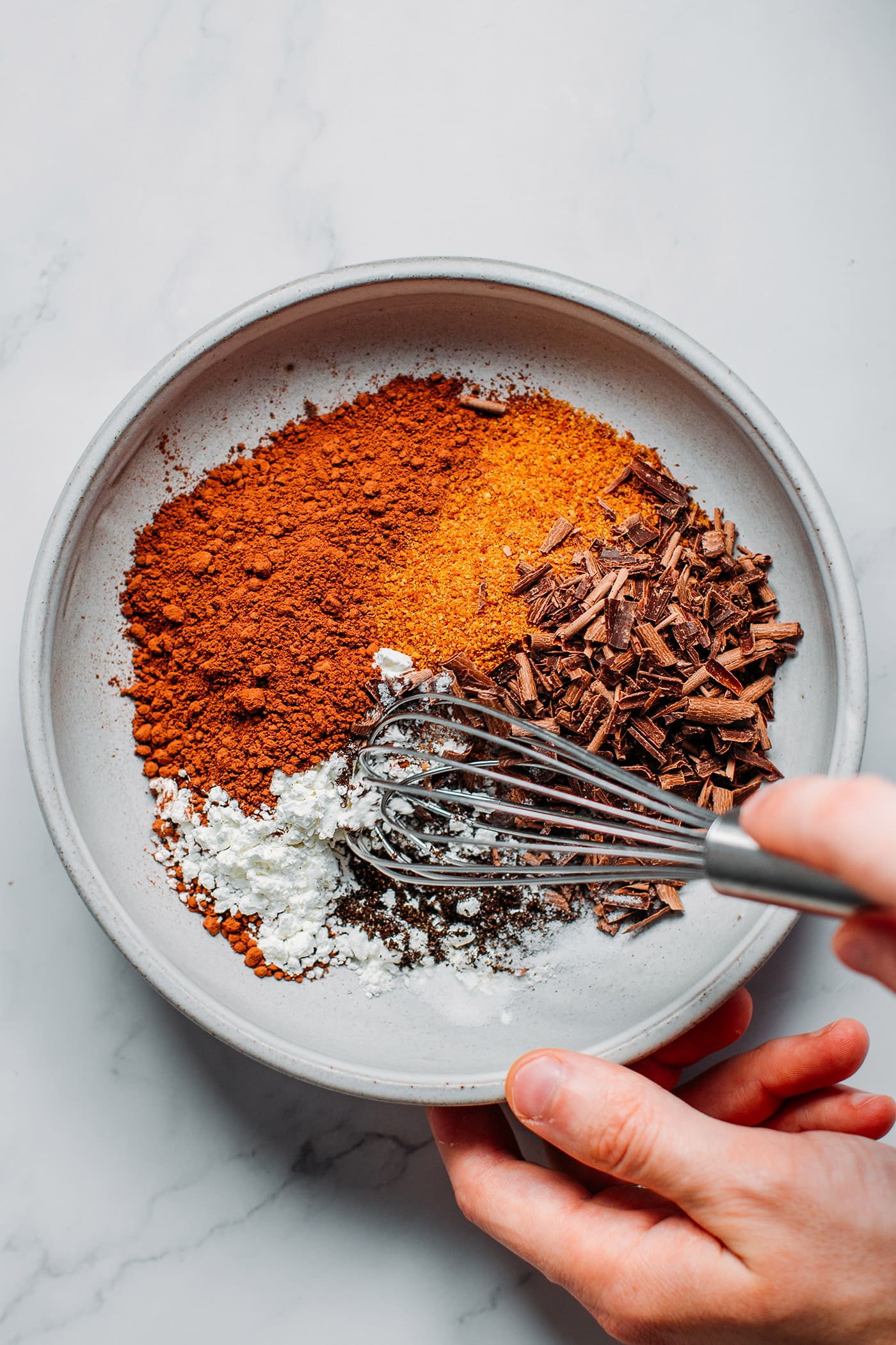 Ingredients like cacao powder, coconut sugar, and shaved chocolate in a bowl.