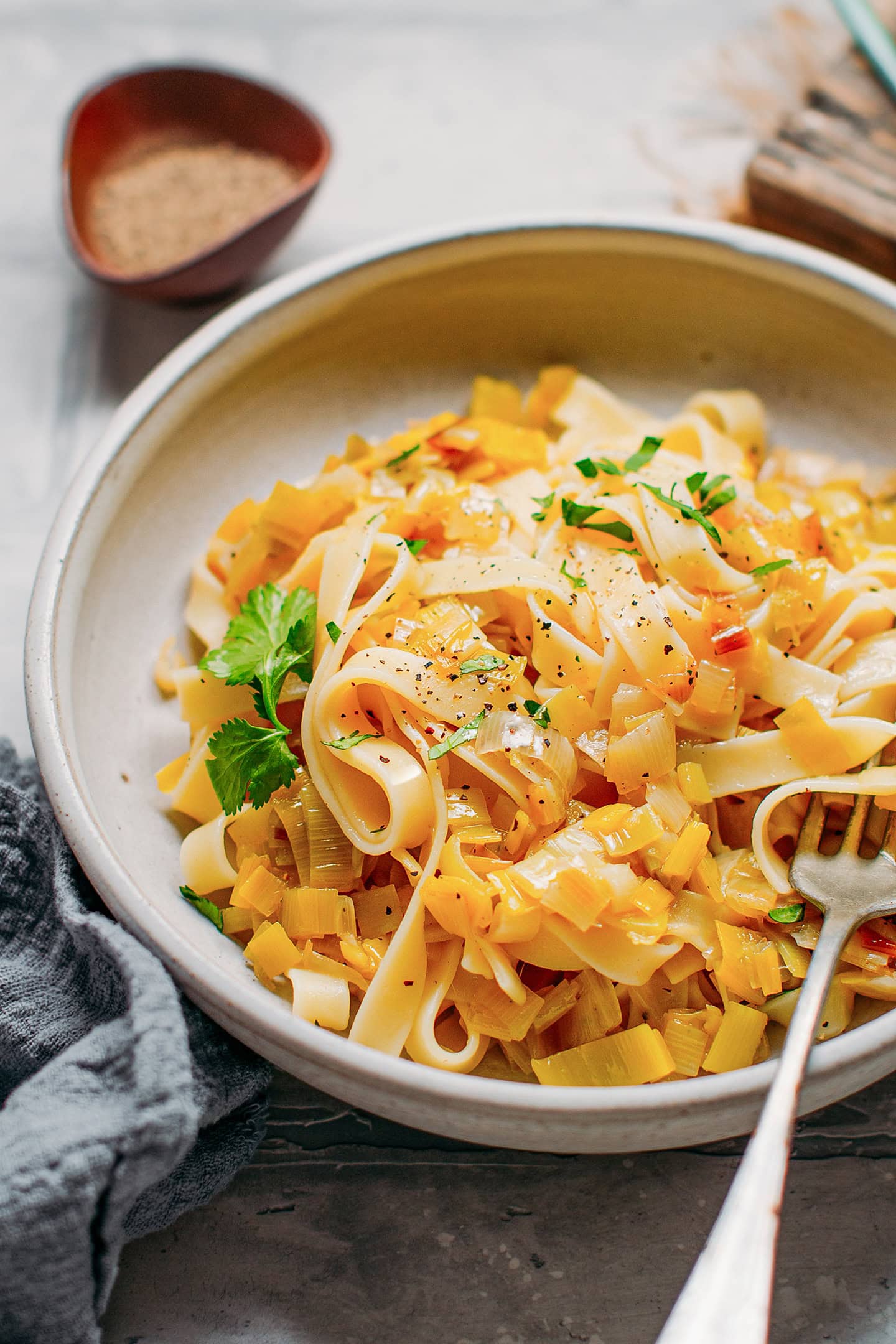 Close up of pasta tossed with melted leeks in a plate.