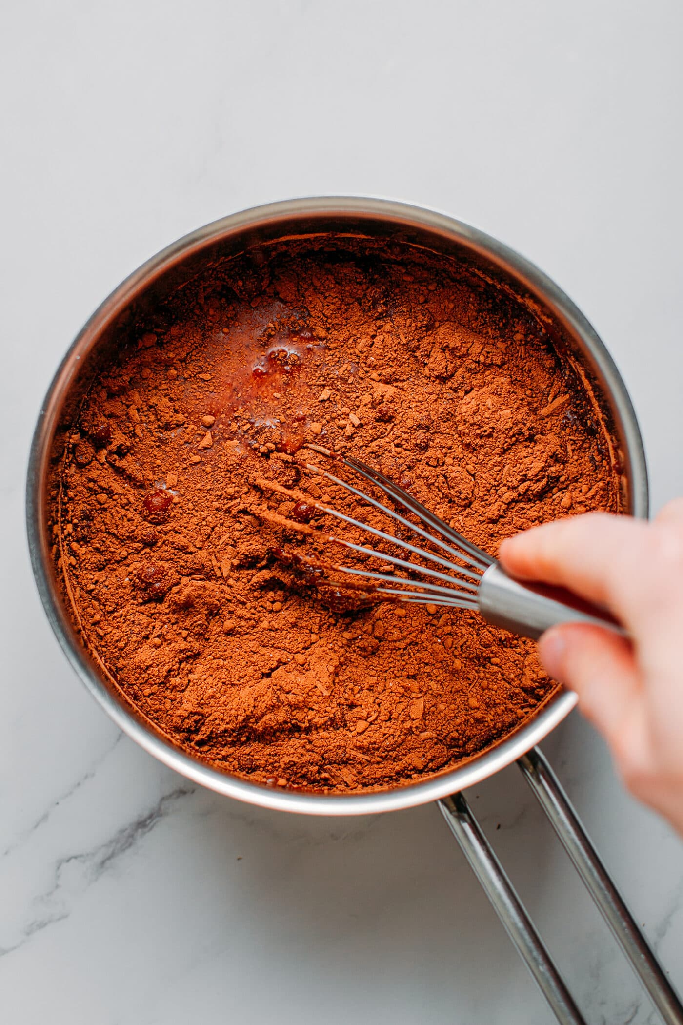 Whisking cacao powder in a saucepan.