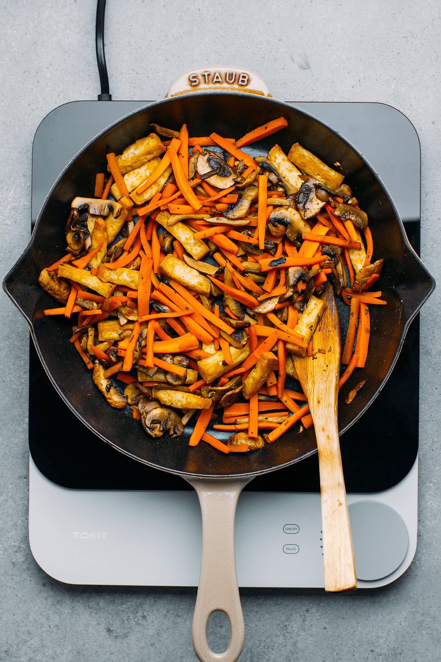 Sautéed carrots, mushrooms, and tofu in a skillet.