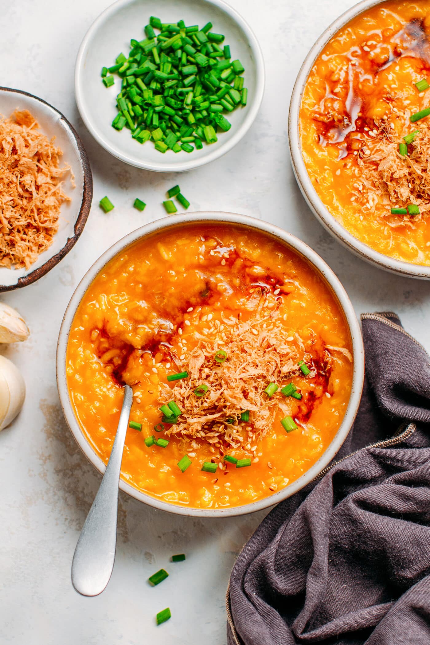 Pumpkin congee topped with vegan meat floss, green onions, and soy sauce.