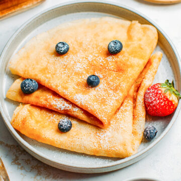 Vegan French crêpes with powdered sugar, blueberries, and strawberries.