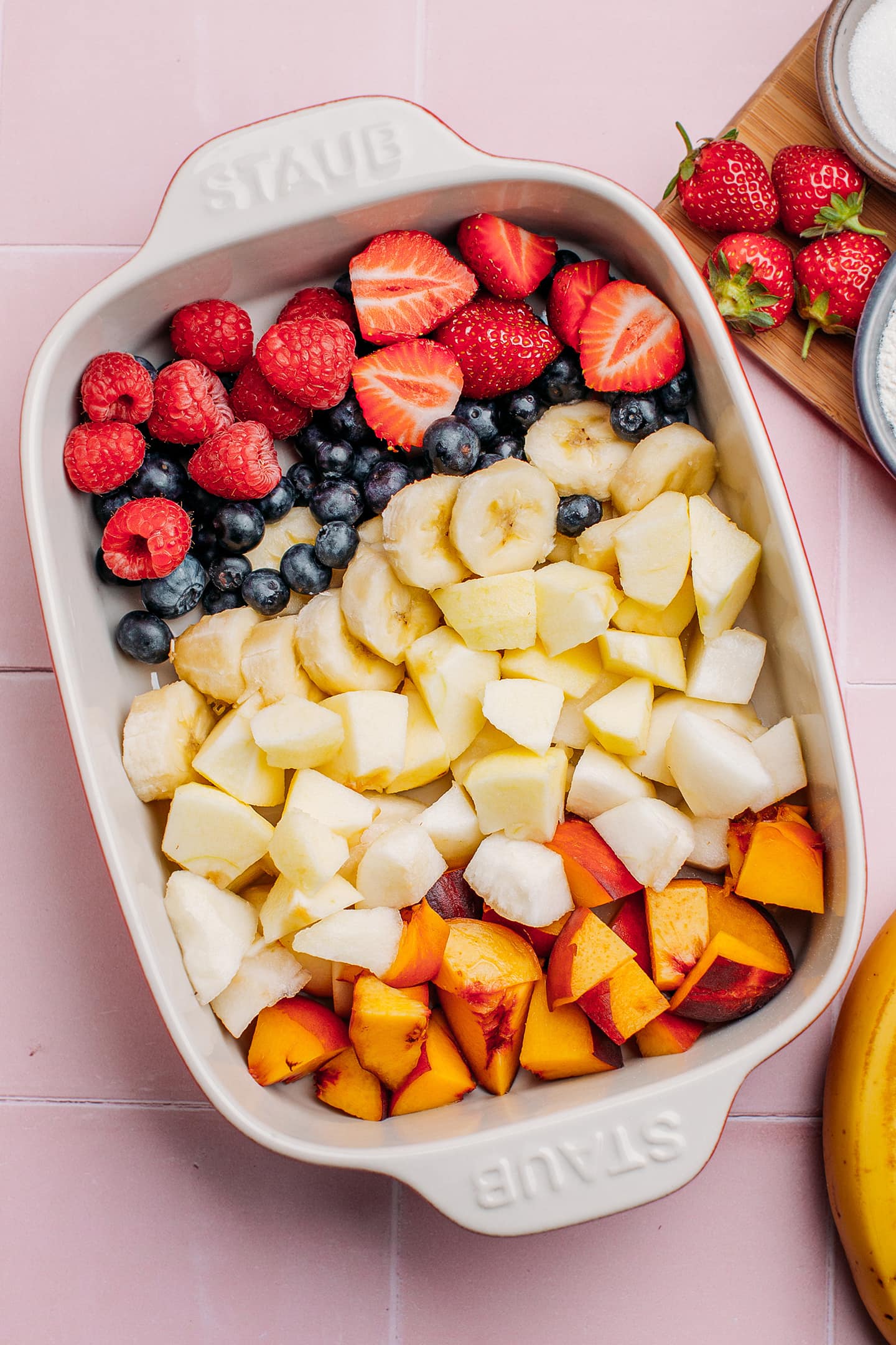 Bananas, raspberries, pears, and apples in a baking dish.