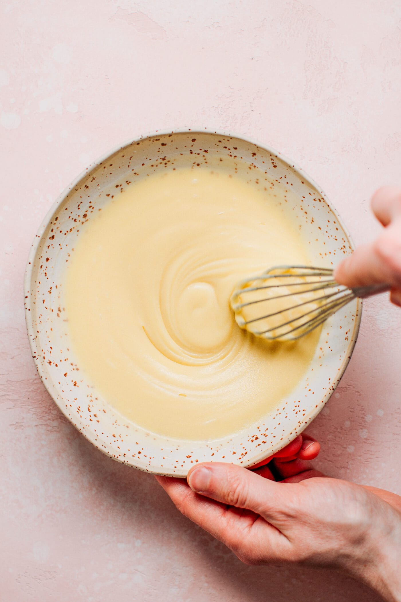 Whisking melted cacao butter with powdered sugar.