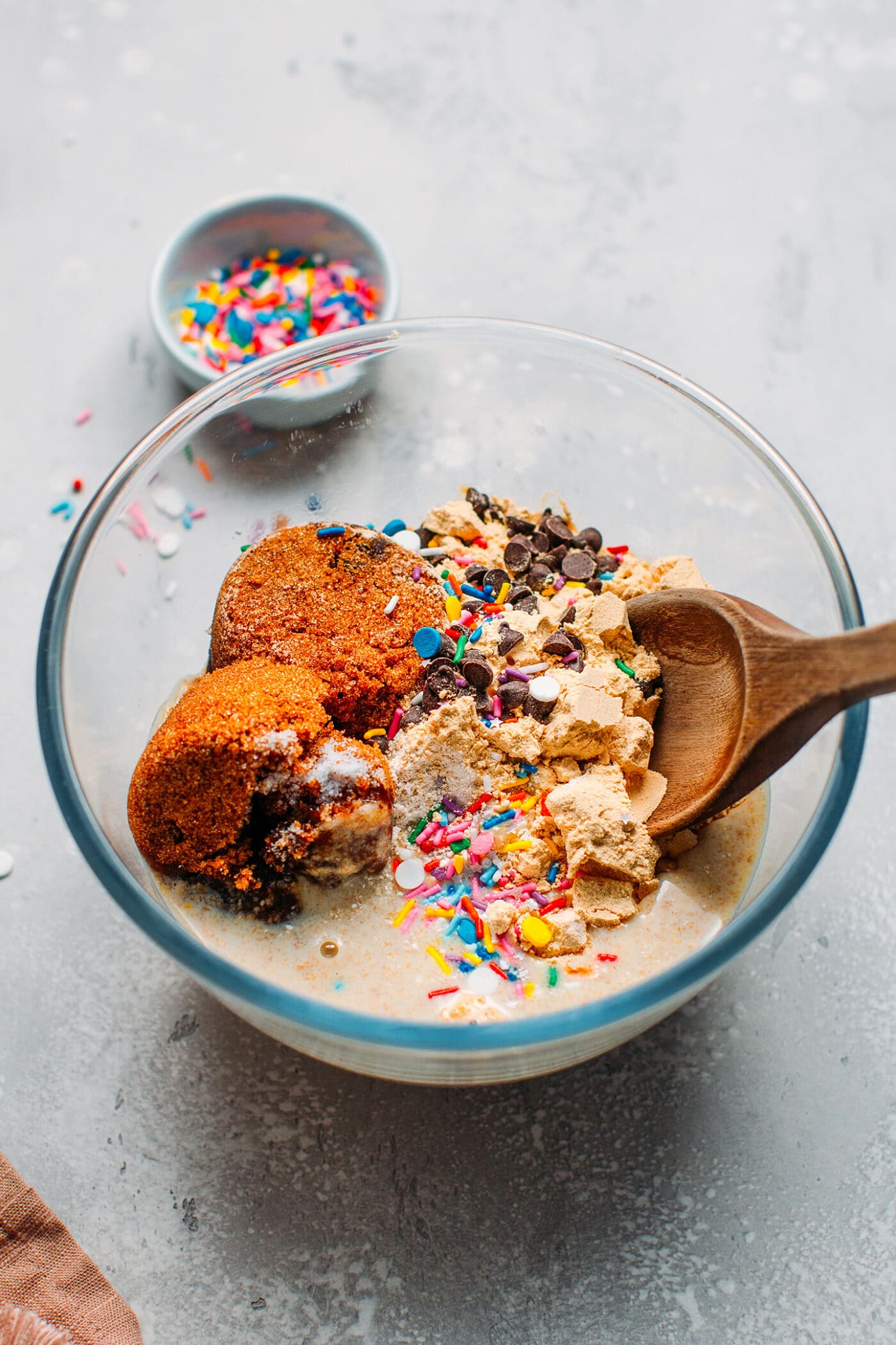 Oat flour, protein powder, coconut sugar, chocolate chips, and sprinkles in a bowl.