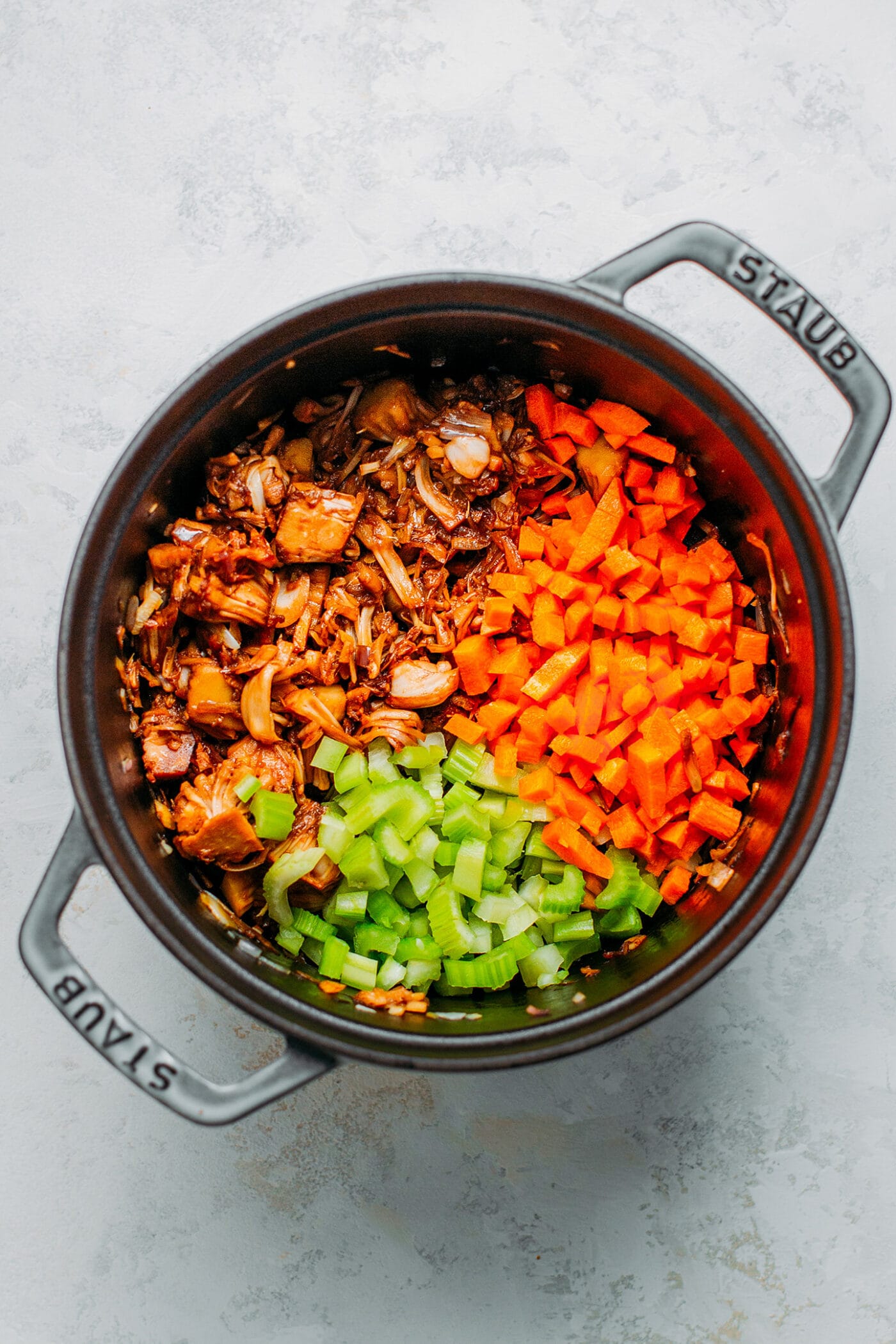 Sautéed jackfruit, diced carrots, and celery in a Dutch oven.