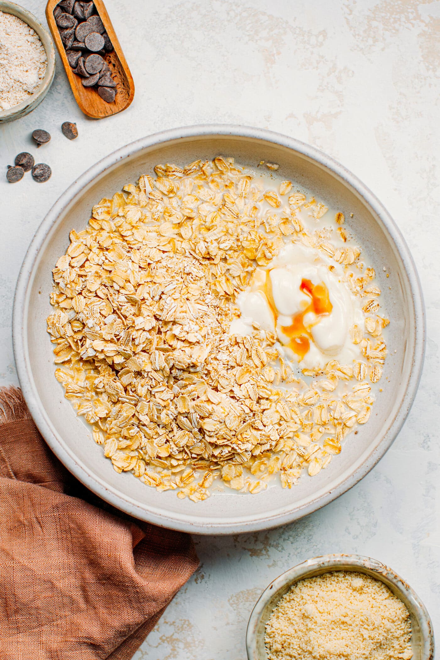 Rolled oats, almond milk, and yogurt in a bowl.