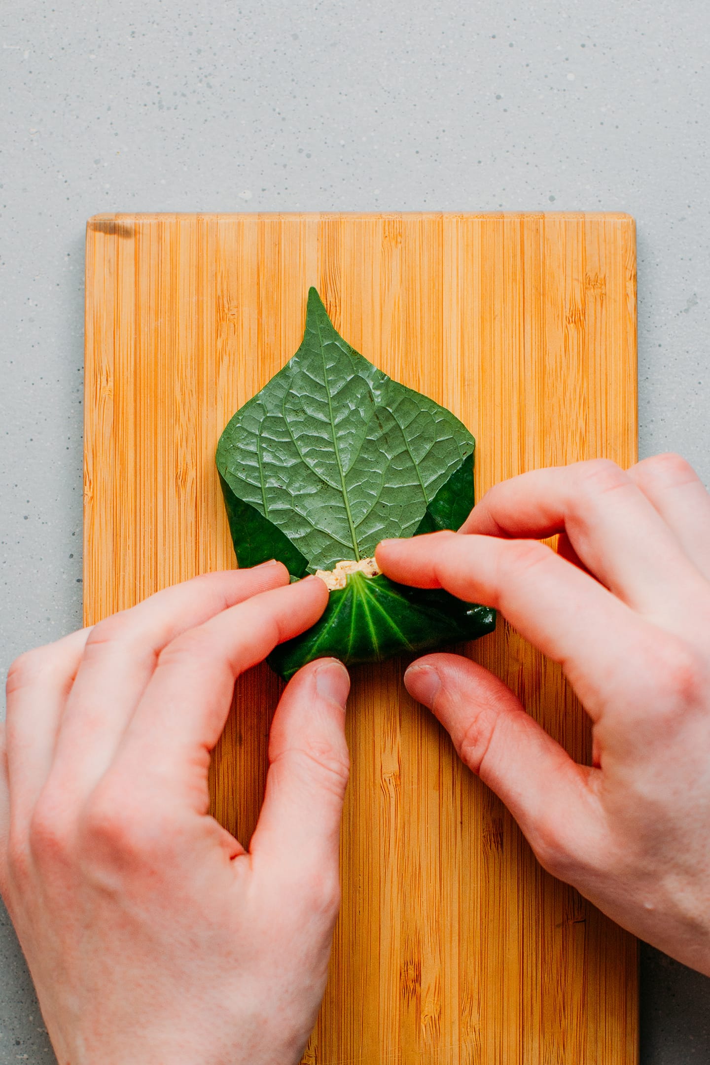 Rolling up a tofu filling in betel leaves.