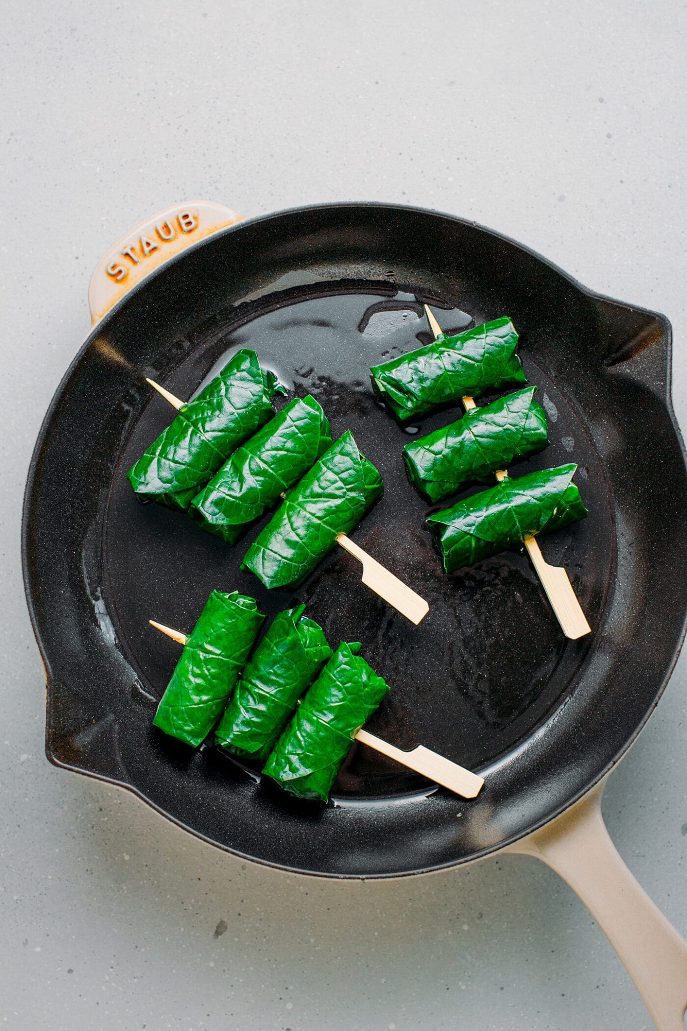 Frying stuffed betel leaves in a skillet.