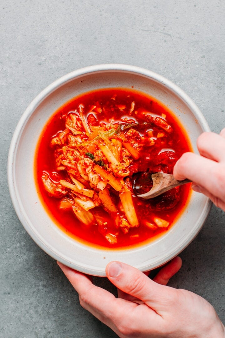 Mixing kimchi with gochujang, sugar, vinegar, and soy sauce.