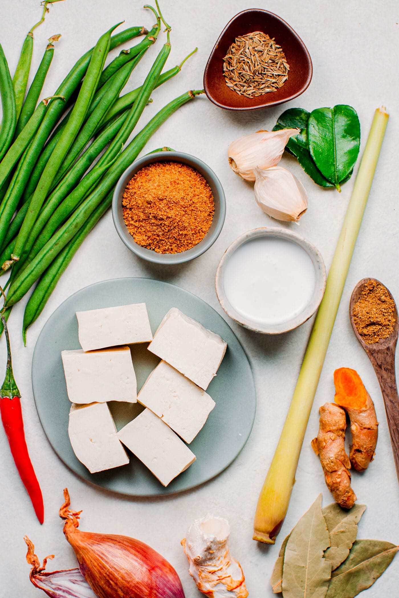 Ingredients like tofu, green beans, turmeric, lemongrass, and shallots.