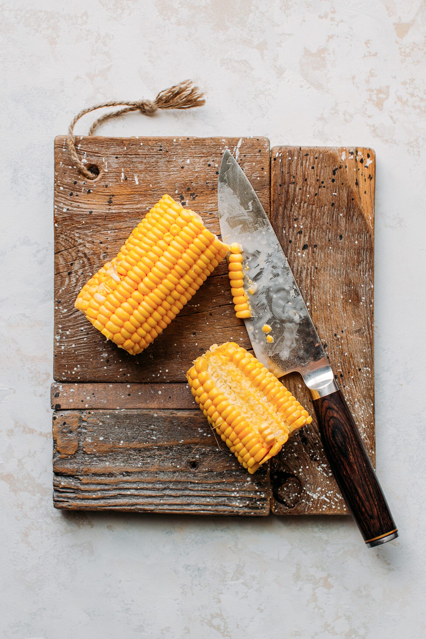 Chopped ears of corn on a wood board.