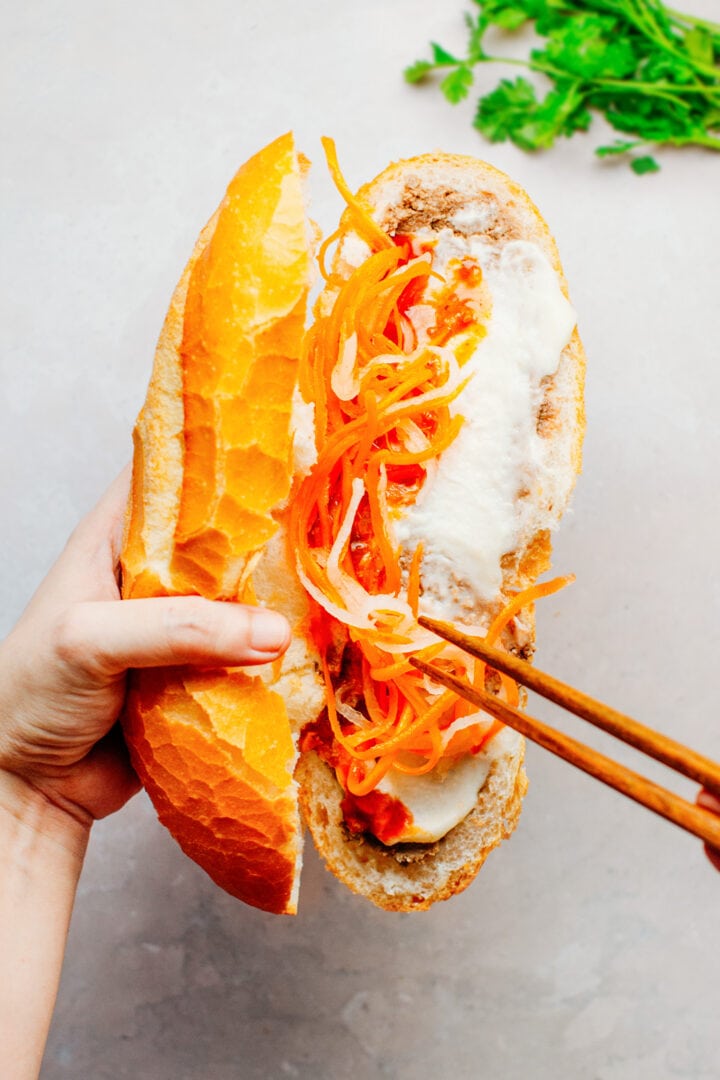 Filling vegan banh mi sandwich with carrot and daikon pickles.