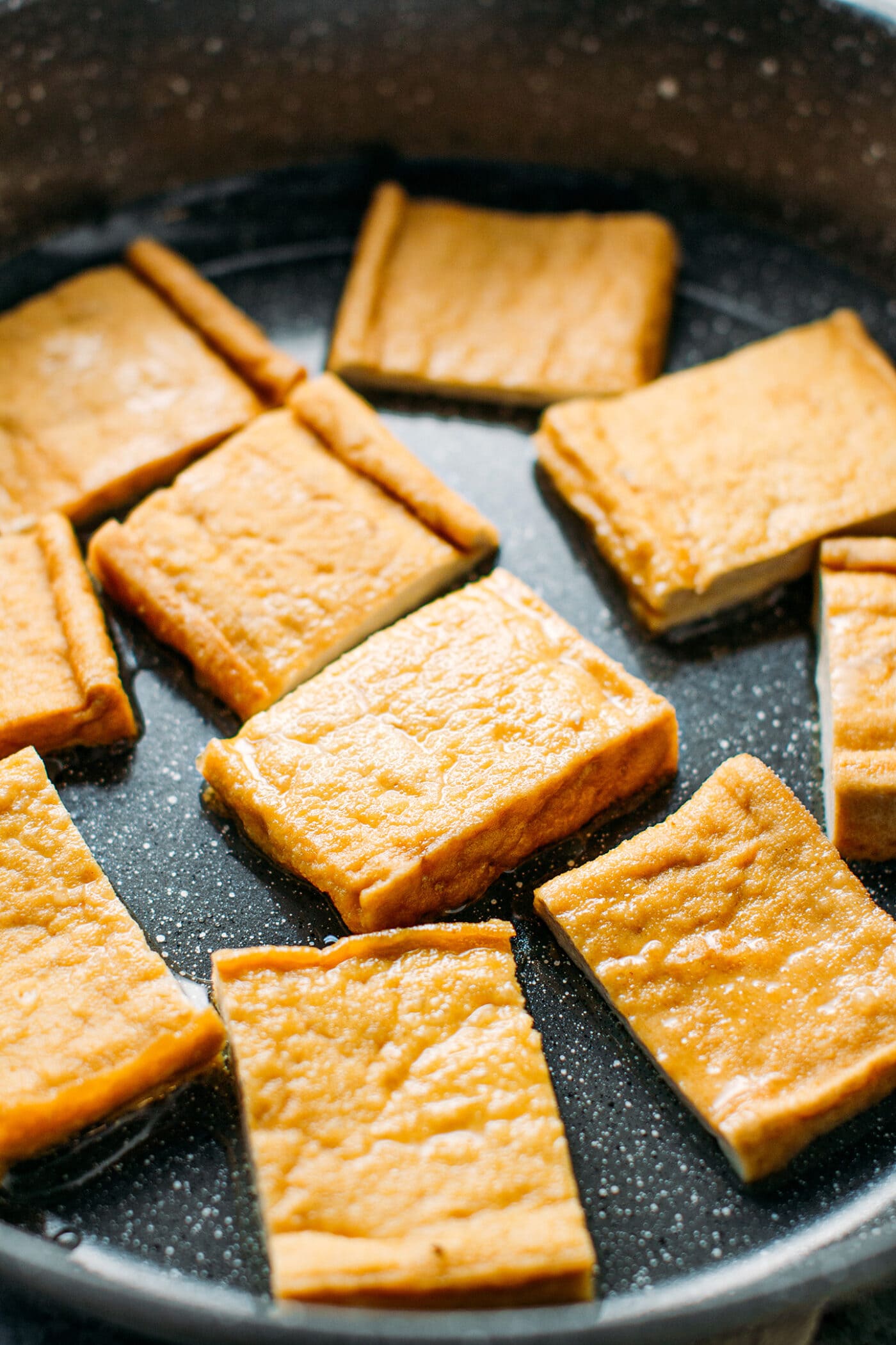 Fried tofu slices in a skillet.