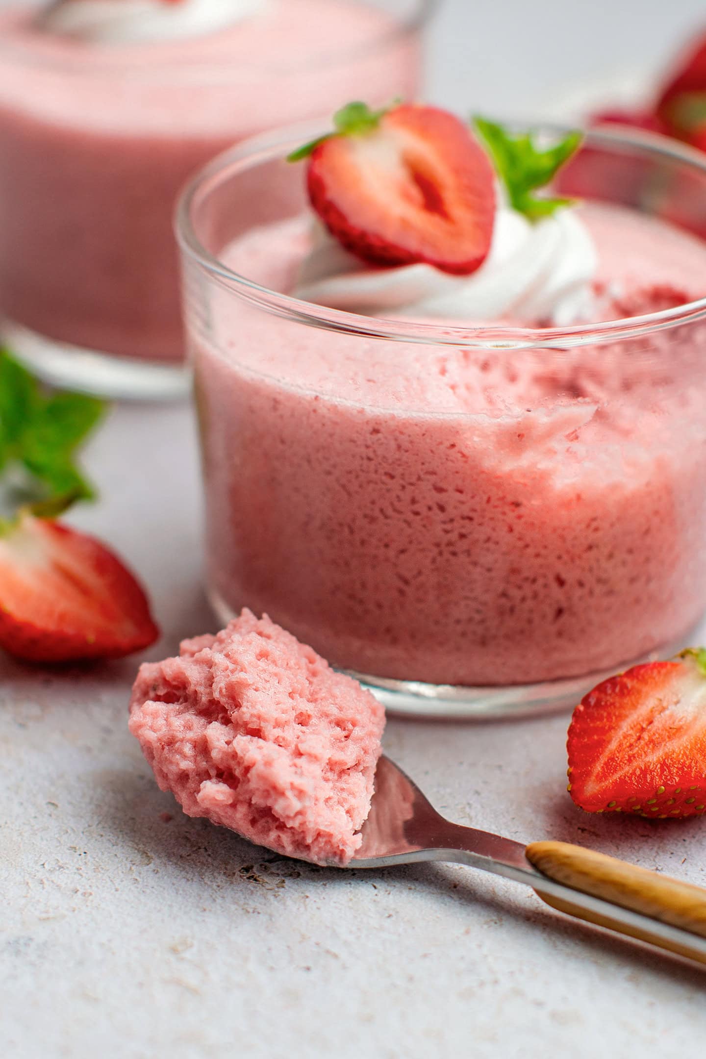 Spoonful of strawberry mousse next to a ramekin.