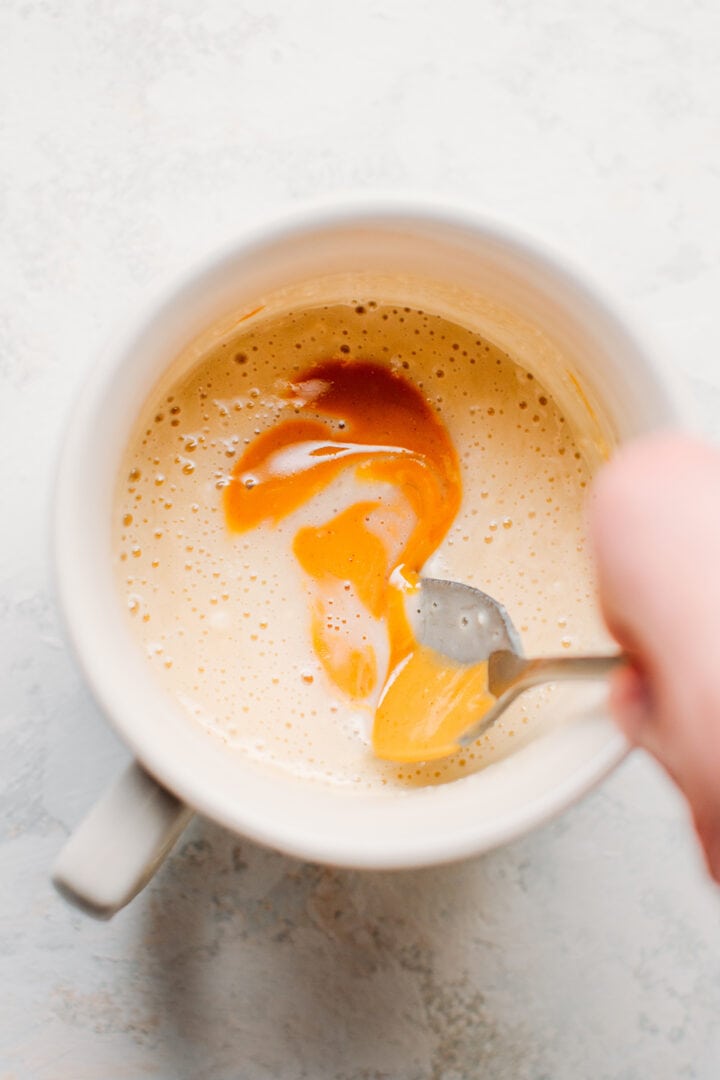 Stirring peanut butter into a mug cake batter.