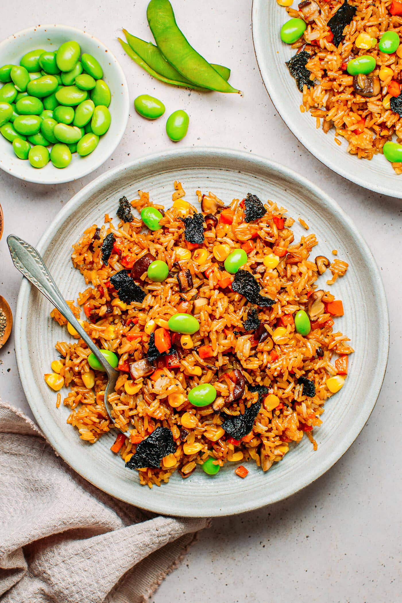 Fried rice with mushrooms, corn, carrots, edamame, and nori on a plate.