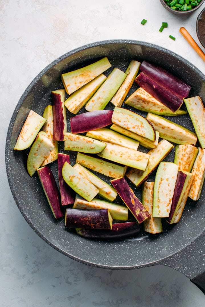 Sliced Chinese eggplants in a skillet.